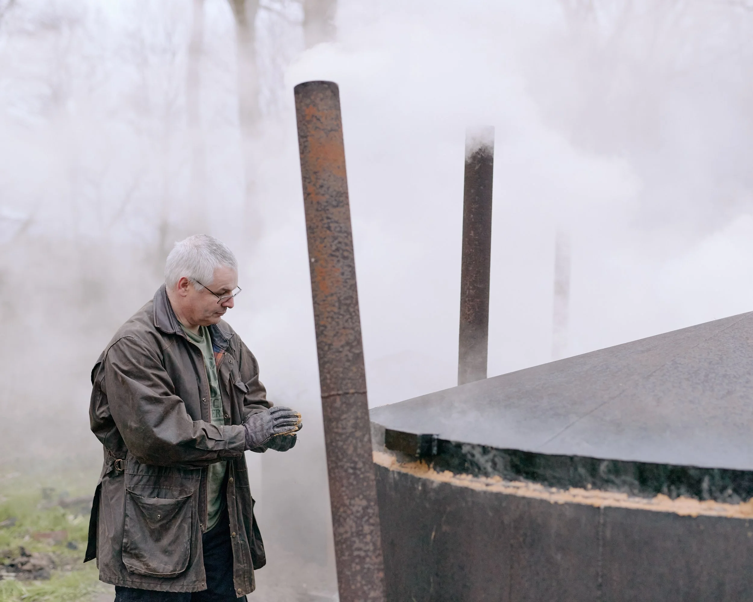 A man sealing a charcoal kiln with sand in Yorkshire, England.