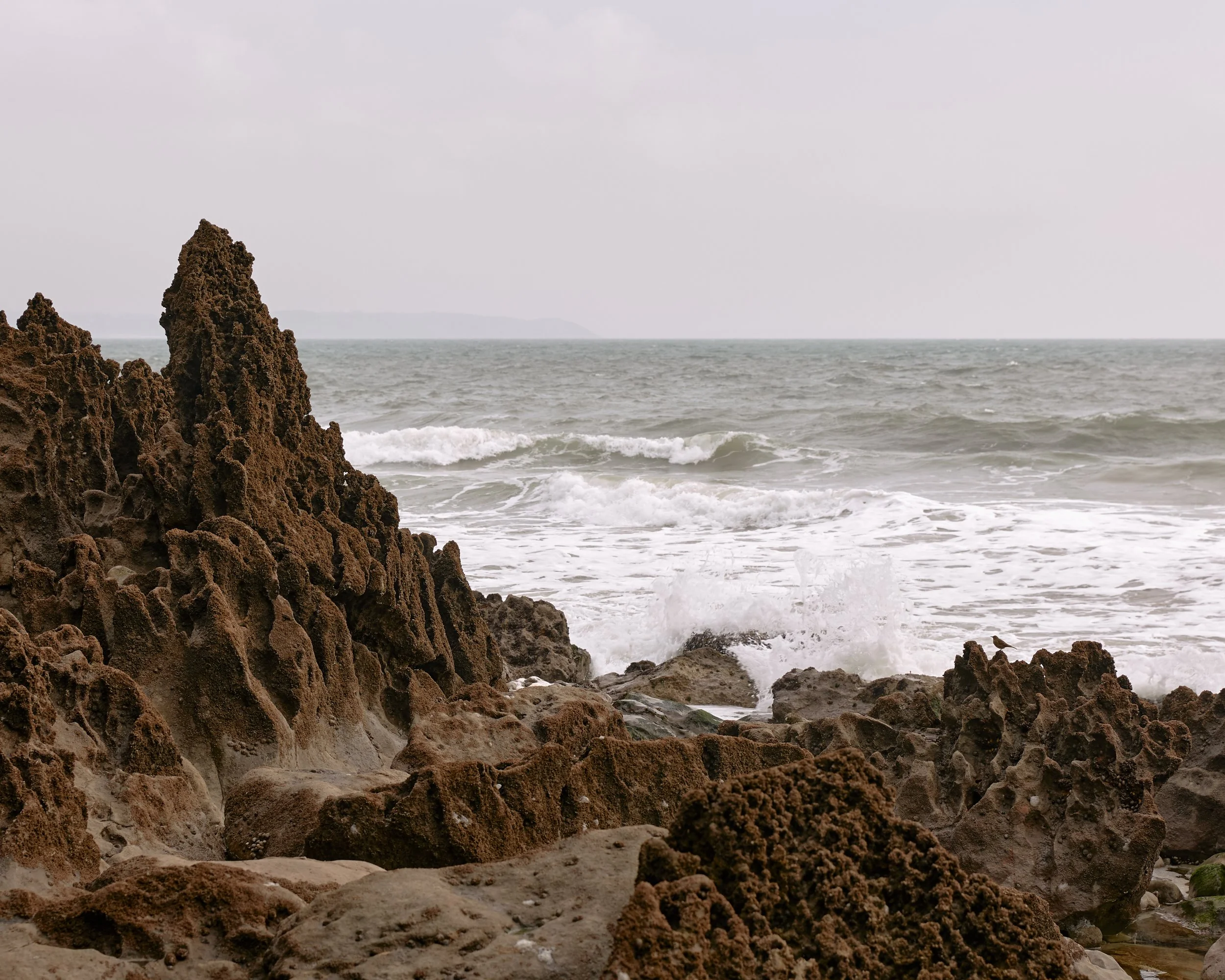 Waves from the Irish Sea breaking against intricately eroded coastal rocks in Pembrokeshire, Wales.