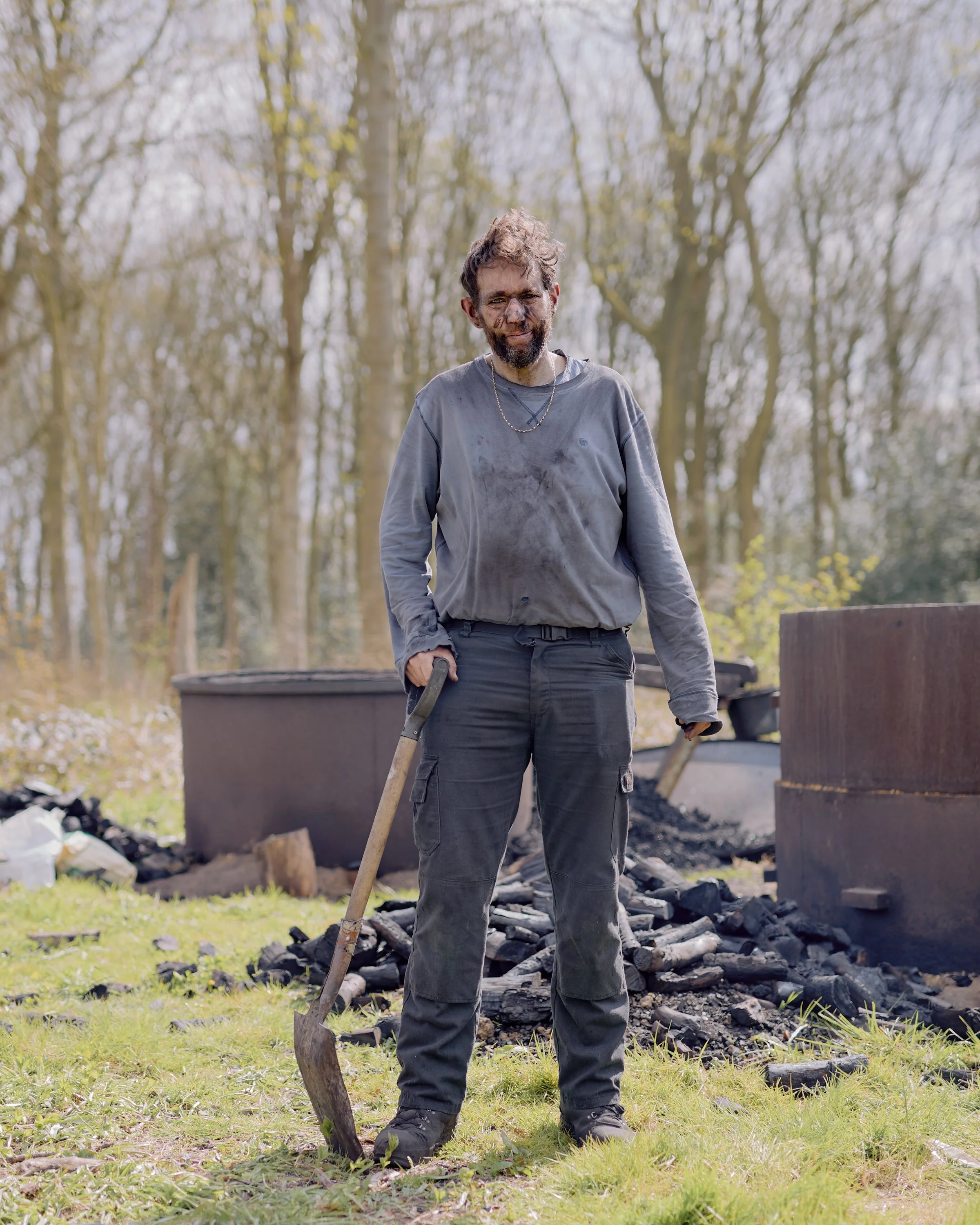 A man shovelling charcoal, dust visible on his clothing, in Yorkshire, England.