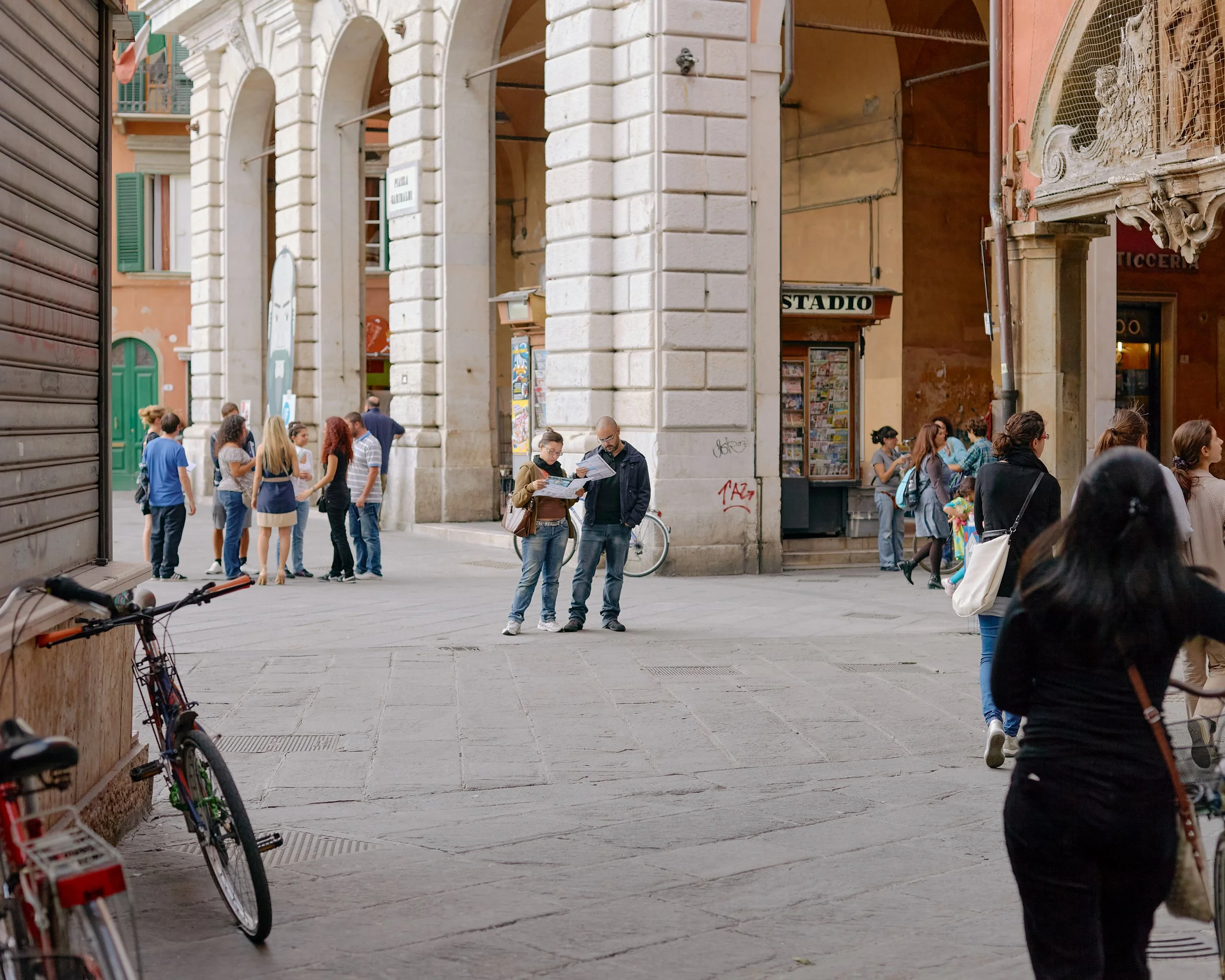 Two people check guides on the streets of Pisa, Italy.