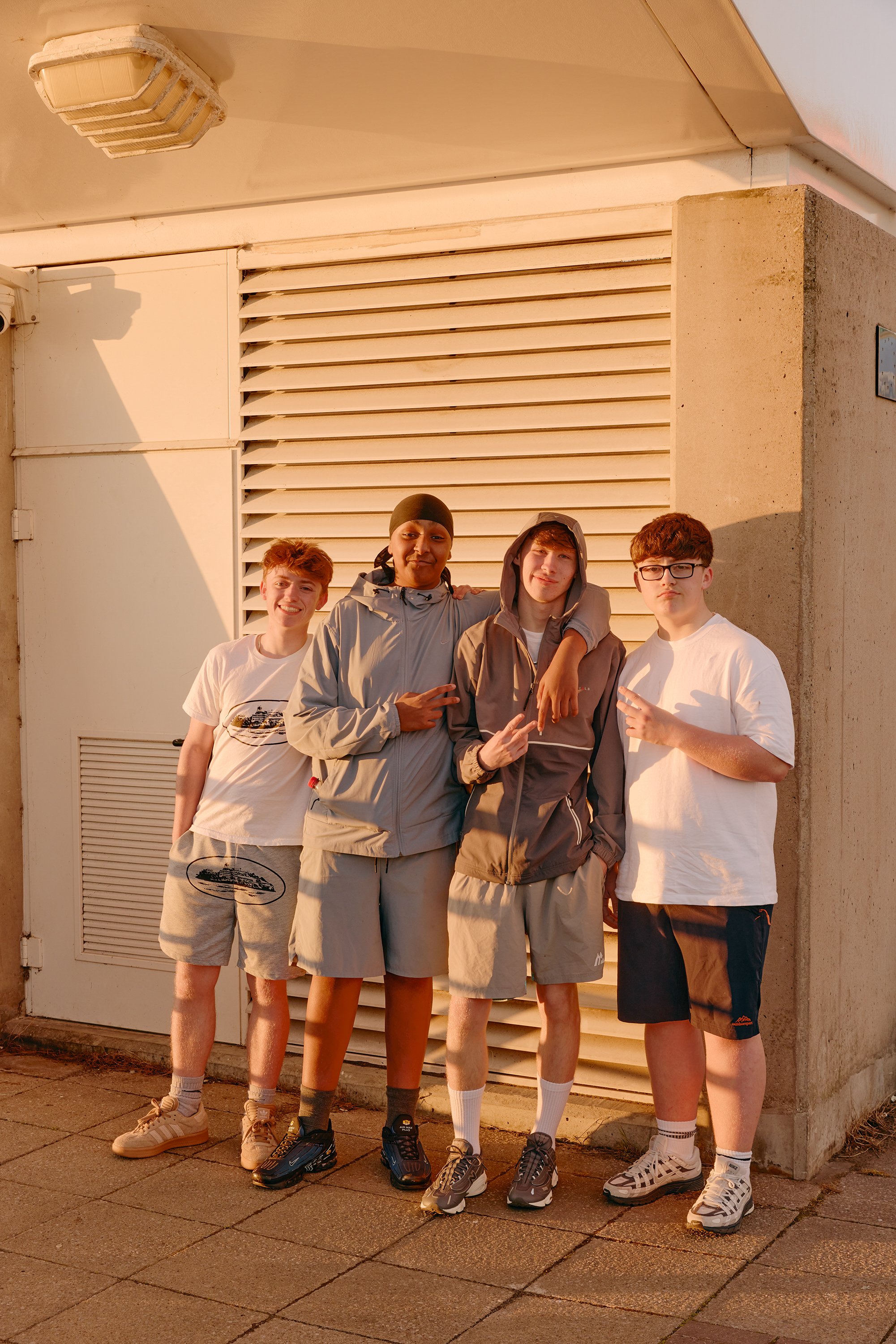 Four teenage boys standing together in warm evening light in Salford.