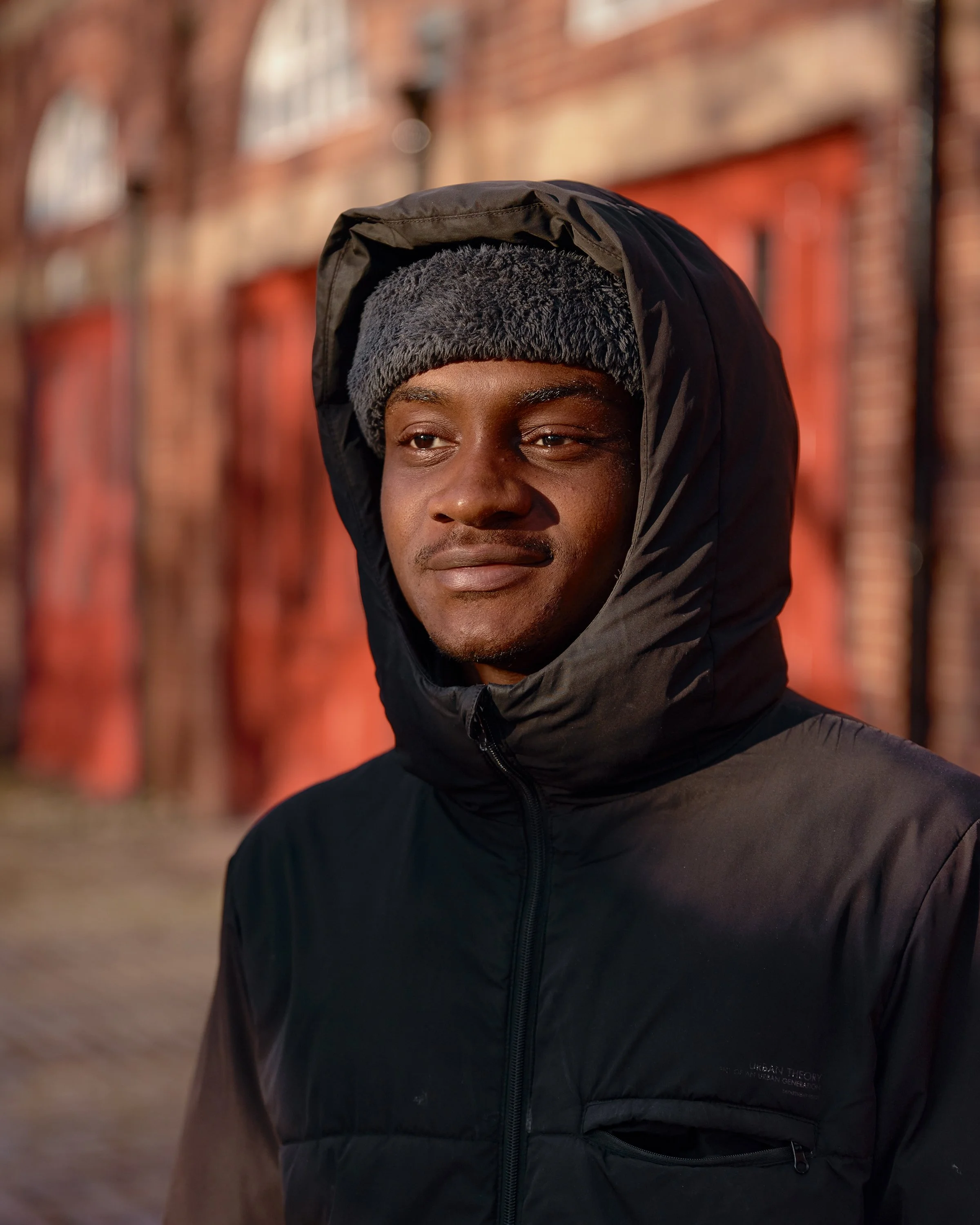 A man standing outside in dappled morning light in Salford, England.