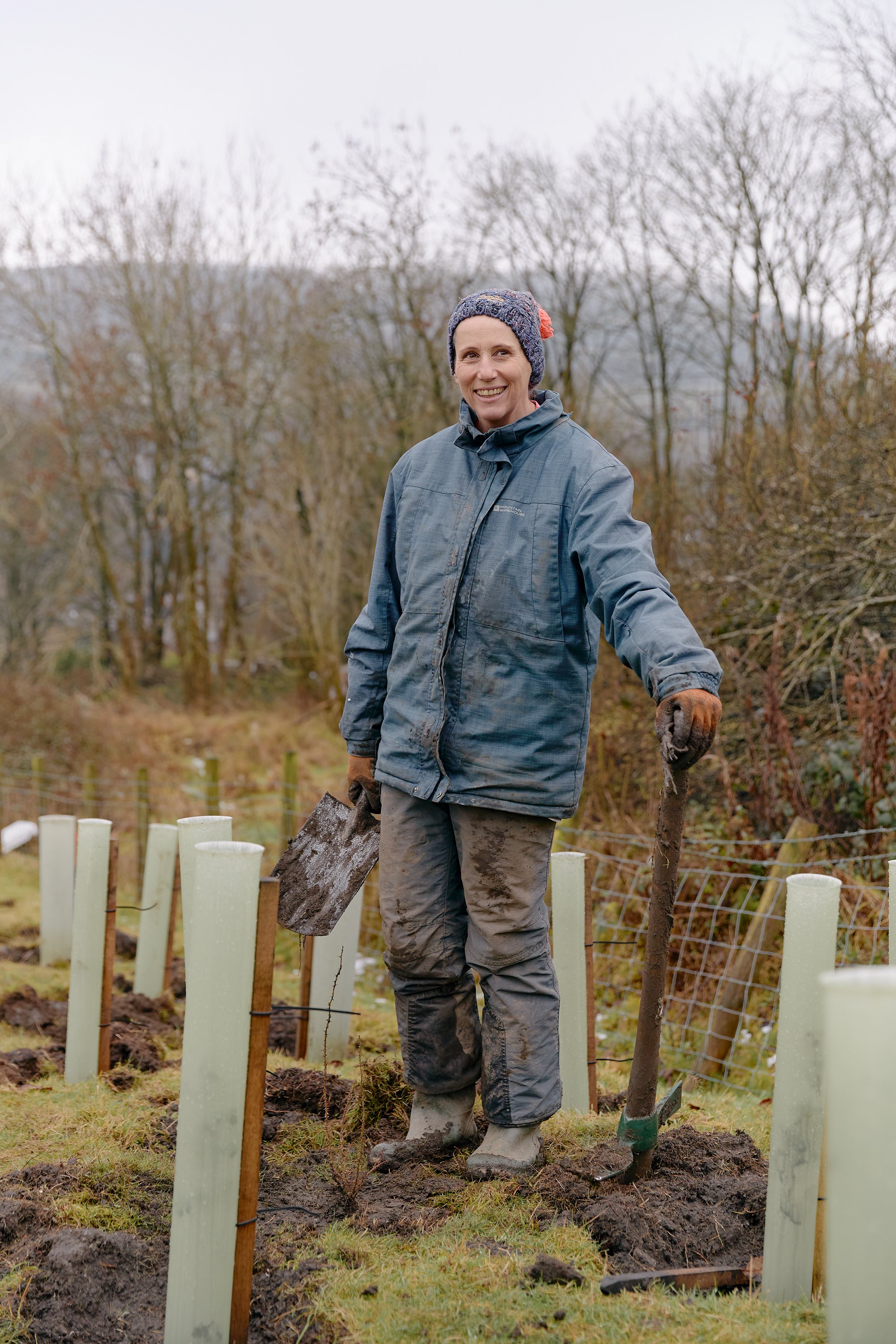 A person planting young trees on a grassy hillside in the Colne Valley.