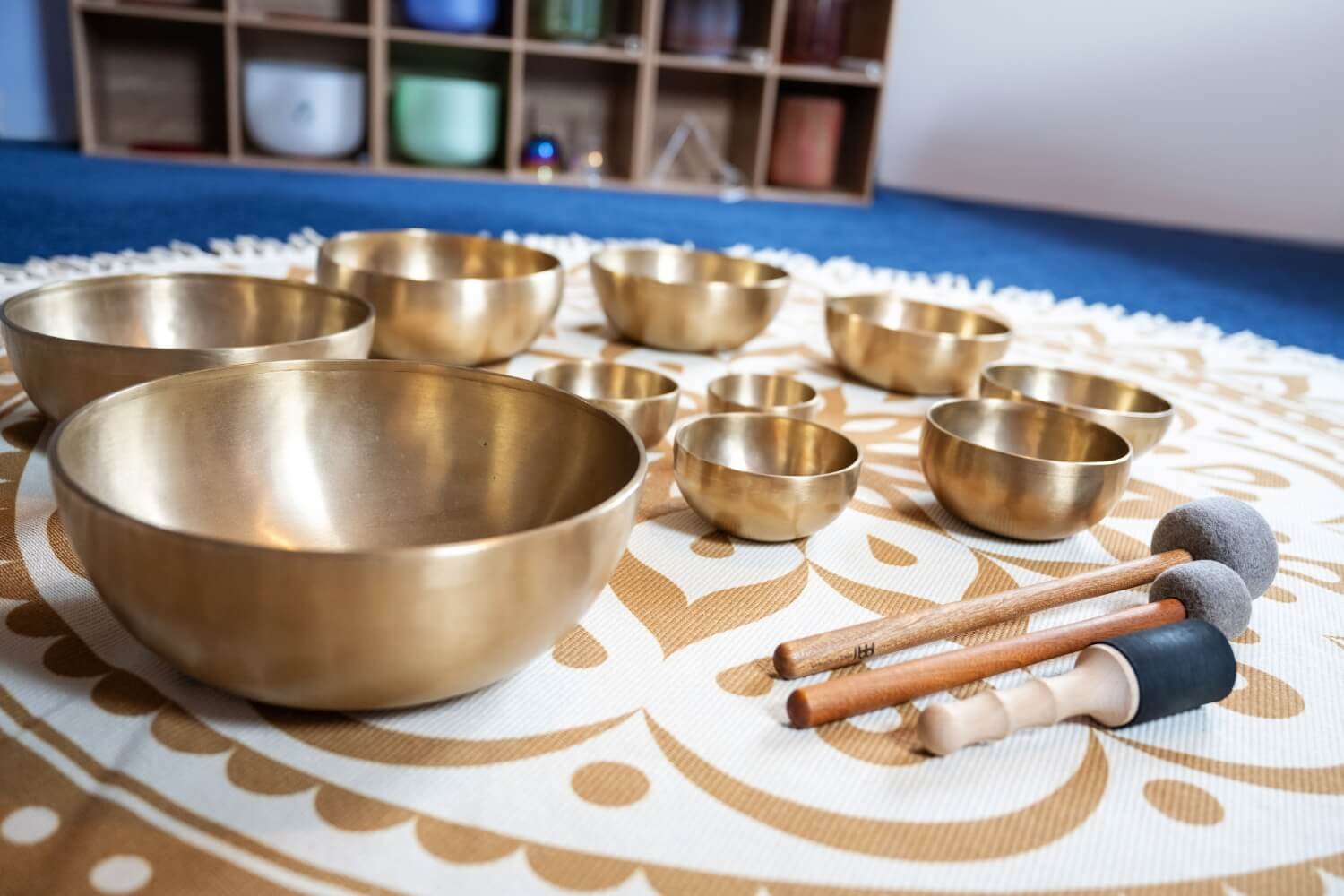 A close up photo of authentic therapeutic Himalayan singing bowls arranged in a precise Fibonacci spiral on a meditation mat, demonstrating sacred geometry principles taught at the Academy of Sound Therapy near Grantham.
