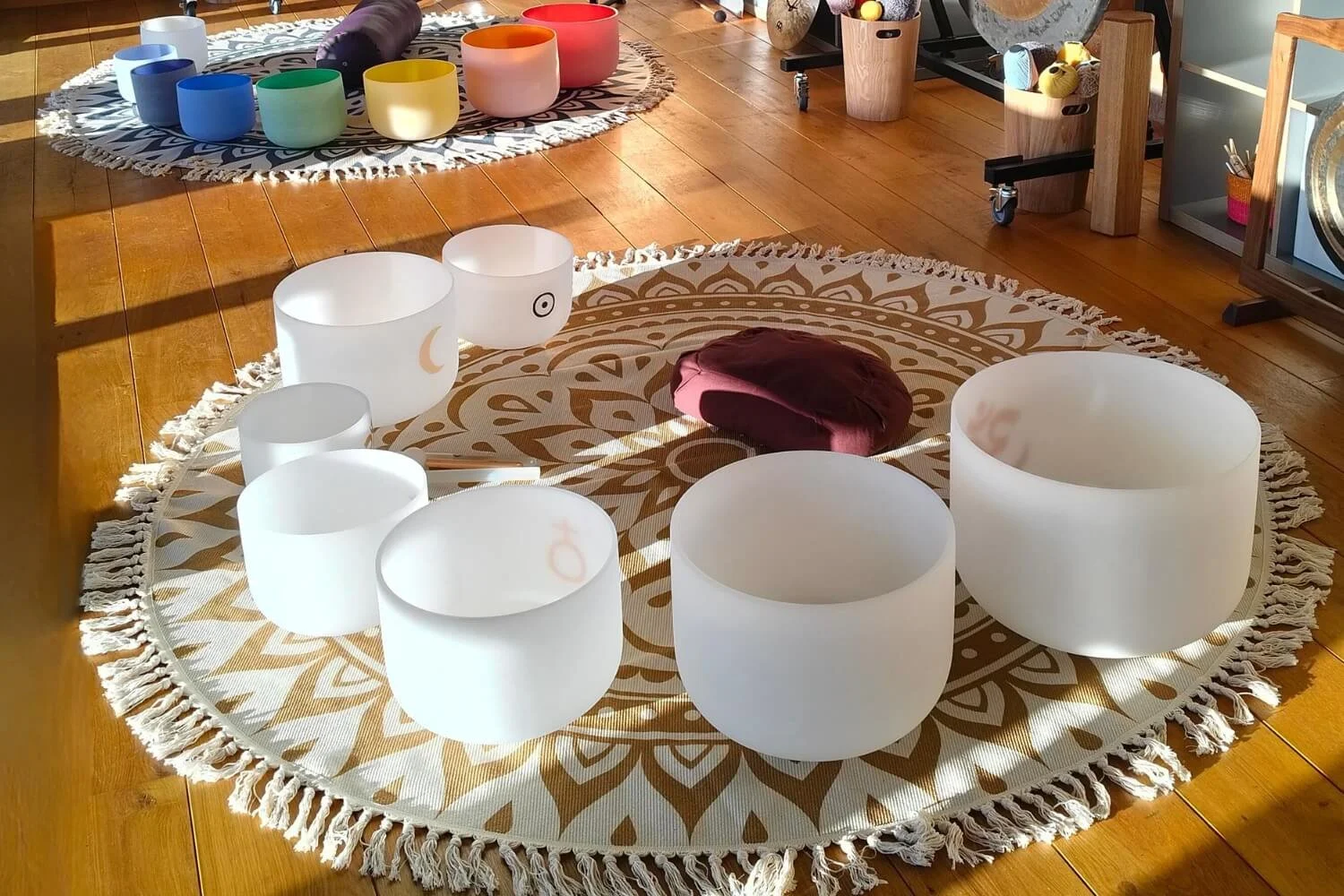 An immersive student training layout at the Academy of Sound Therapy near Grantham, showcasing two Meinl meditation mats prepared with a full set of frosted crystal chakra bowls and specialized planetary singing bowls for practical hands-on experienc