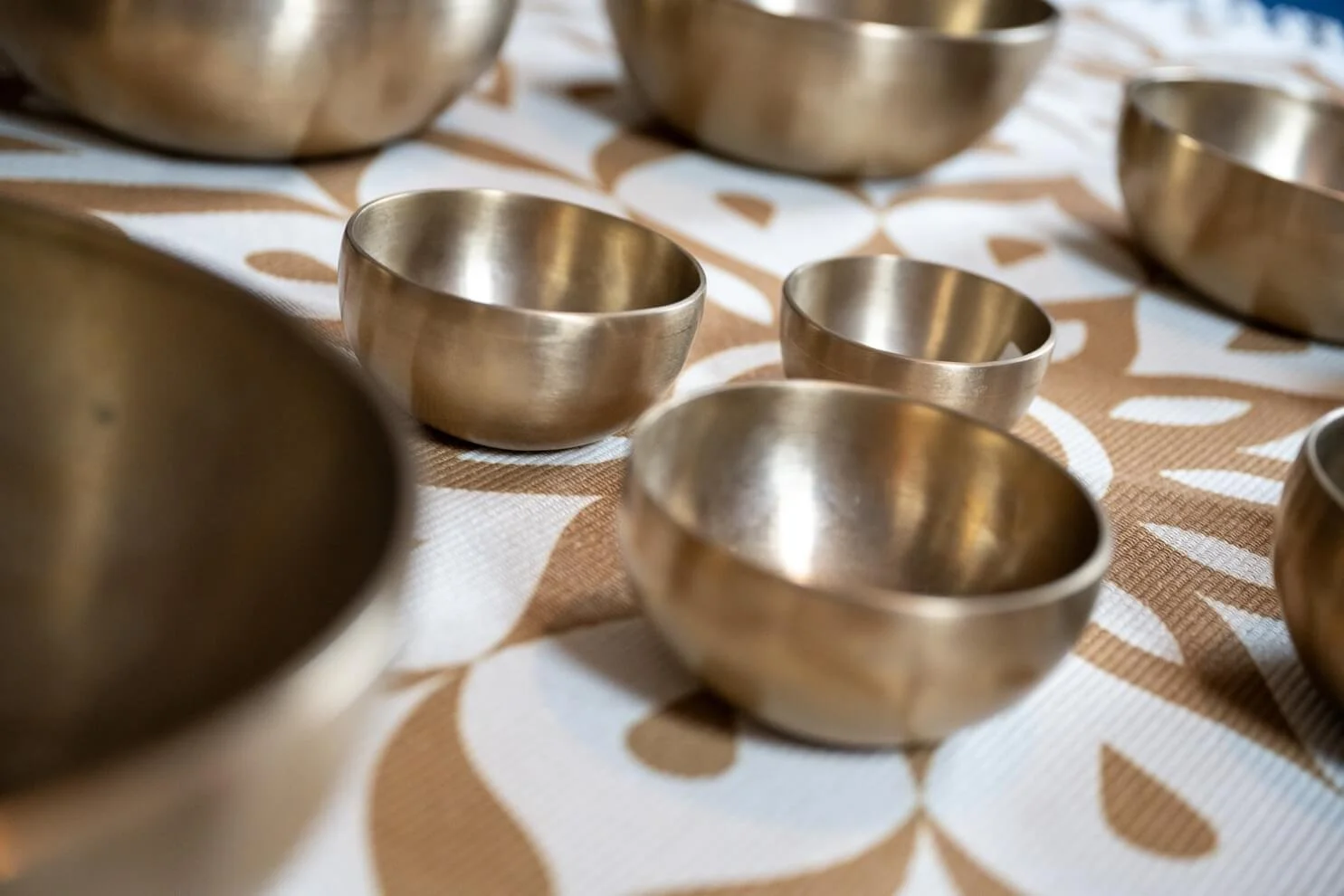 Close up photo of authentic therapeutic Himalayan singing bowls resting on a meditation rug, used during advanced sound therapy masterclasses and bespoke 1:1 workshops near Grantham.