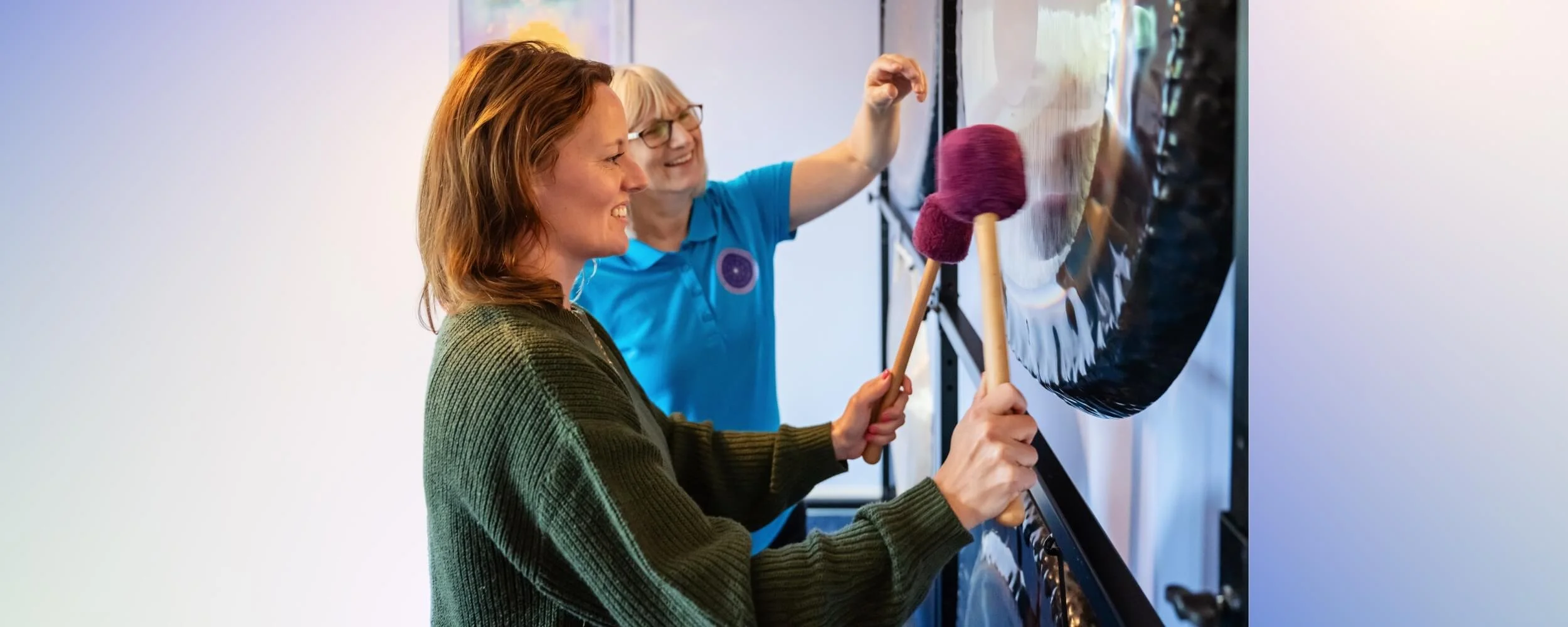 An accredited sound therapy practitioner training session at the Academy of Sound Therapy, showing the tutor Helen Campbell providing professional, hands-on mallet instruction to a student during an intensive gong module near Grantham.