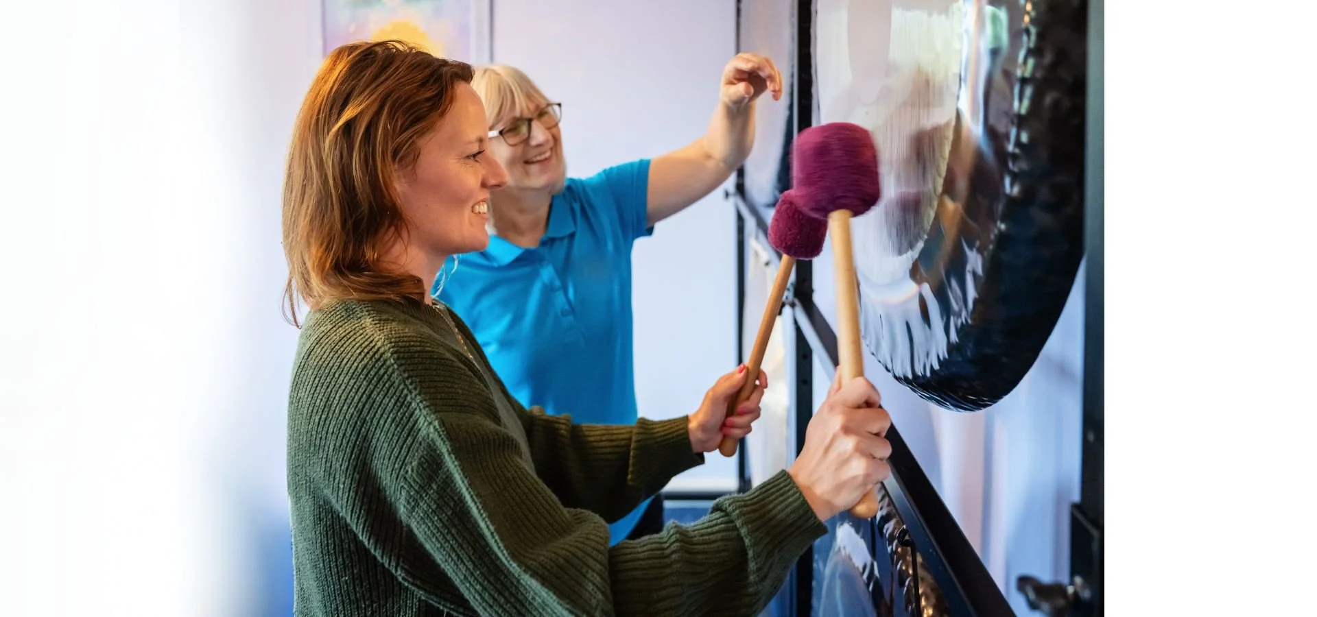 The tutor, Helen, helping a student with gong techniques. The student is stood in front of a Paiste 38" Symphonic Gong and she is holding a mallet in each hand.