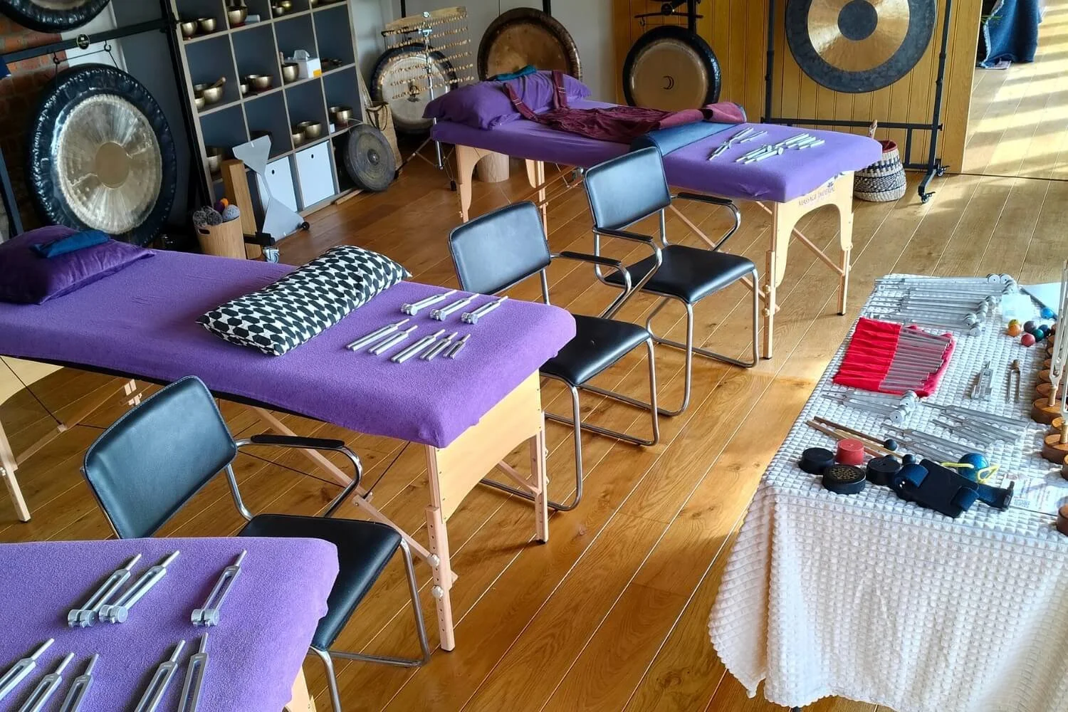 A dedicated tuning fork practitioner training room layout at the Academy of Sound Therapy near Grantham. The studio features individual student learning stations equipped with weighted and unweighted tuning forks alongside the tutor's demonstration a