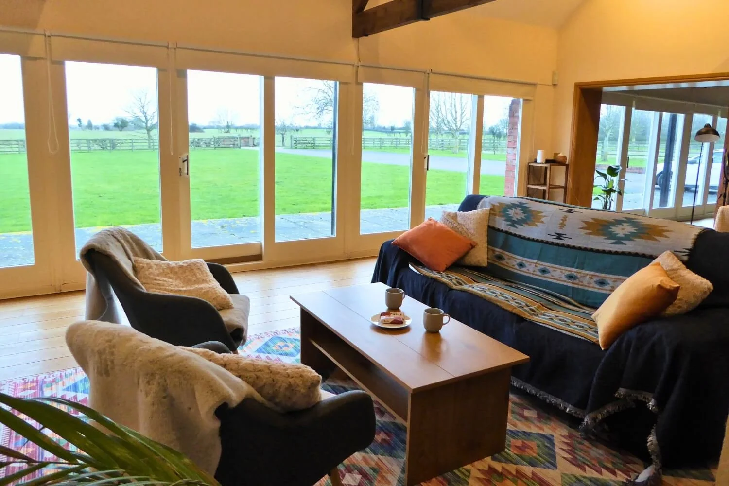 The comfortable relaxation lounge at the Academy of Sound Therapy near Grantham, showcasing our informal sofa seating area where students enjoy tea, biscuits, and a supportive, conversational approach to learning while looking out over peaceful Linco