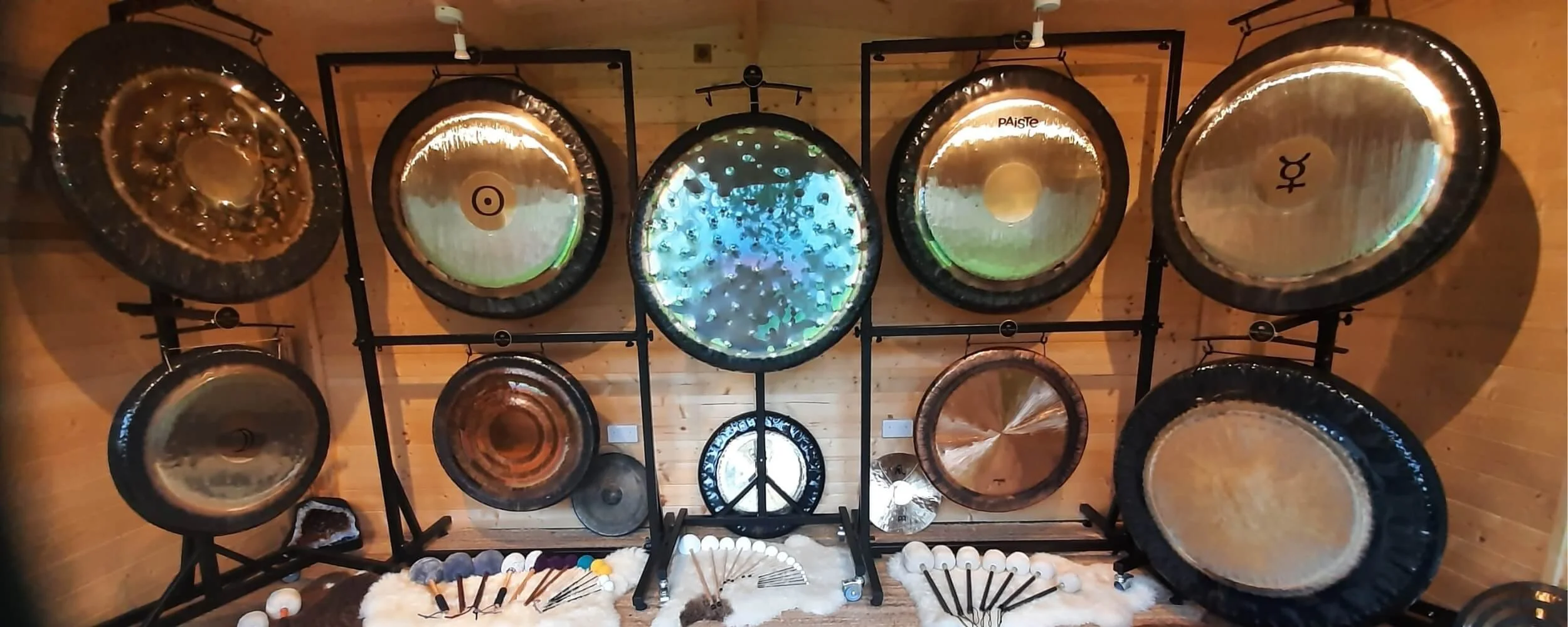 A world-class alignment of professional master gongs arranged inside the private timber cabin training room at the Academy of Sound Therapy in Stretton, Rutland.