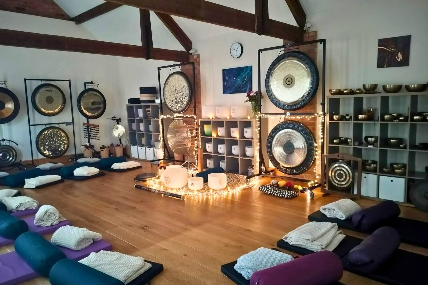 Restorative sound bath session layout at the Academy of sound Therapy in Ingoldsby, near Grantham. The sanctuary features gongs and singing bowls arranged in front of comfortable mats prepared with bolsters, cushions, and warm blankets for guests.