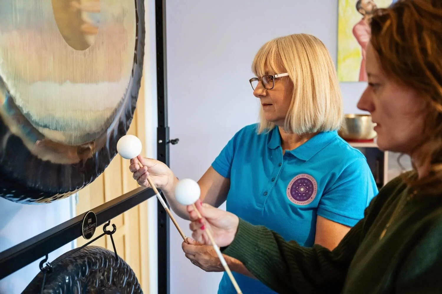 A professional tutoring session at the Academy of Sound Therapy near Grantham, showcasing tutor Helen Campbell refining a student's friction gong techniques to create deep therapeutic resonance during a certified course.