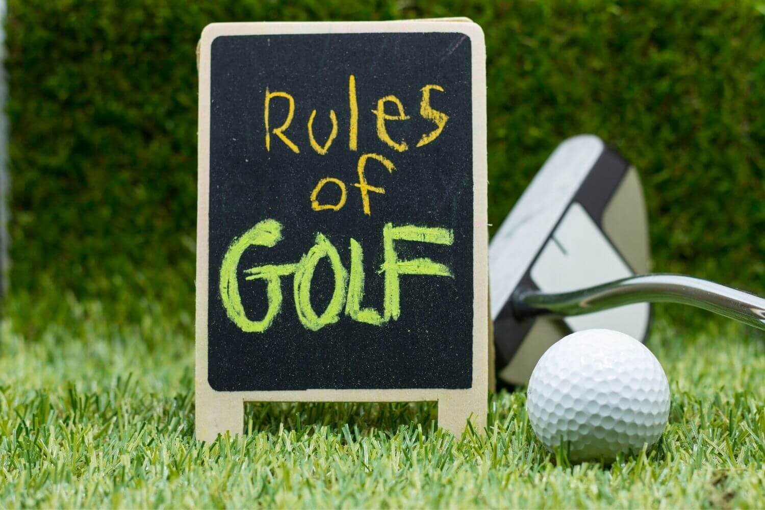 Chalkboard rules of golf sign next to club and ball