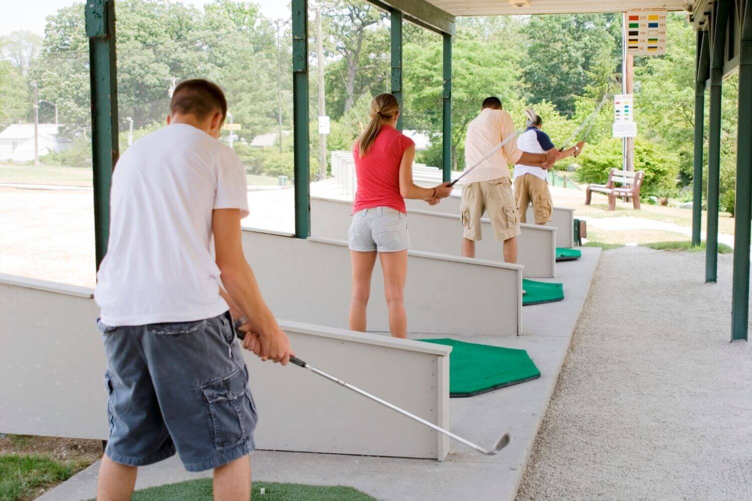 Woman and men practicing golf at a driving range
