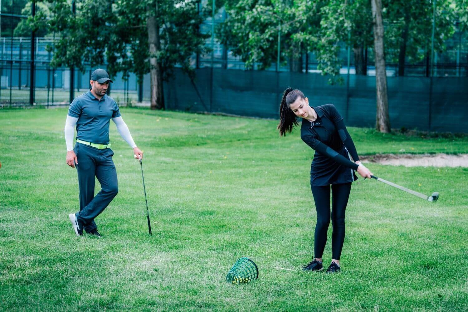 Woman practicing golf with a male golf instructor