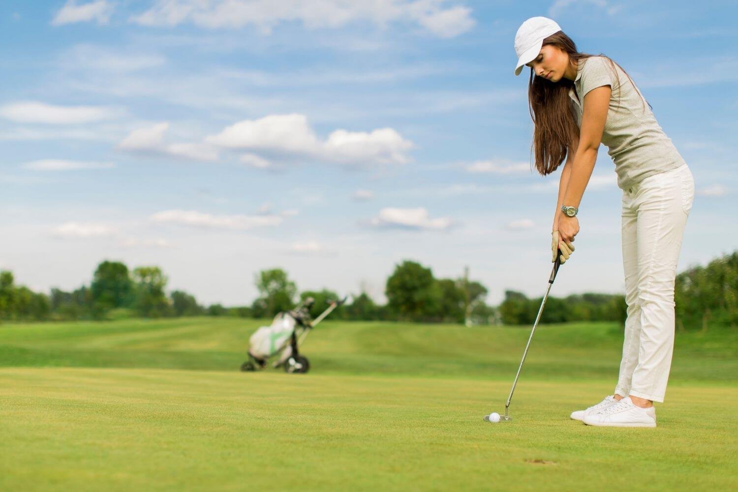 Female golfer putting ball into the hole