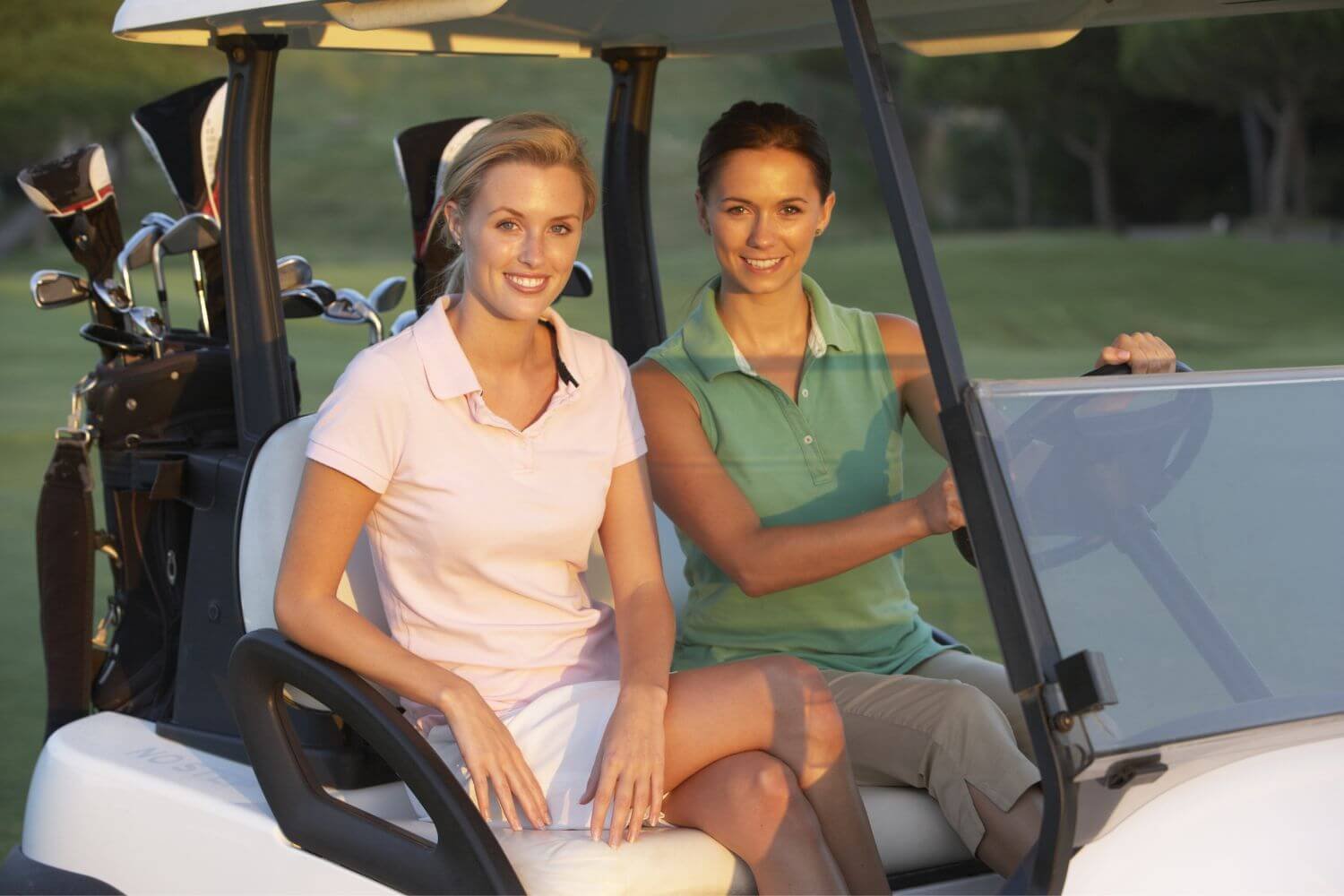two women golfers smiling in a golf cart