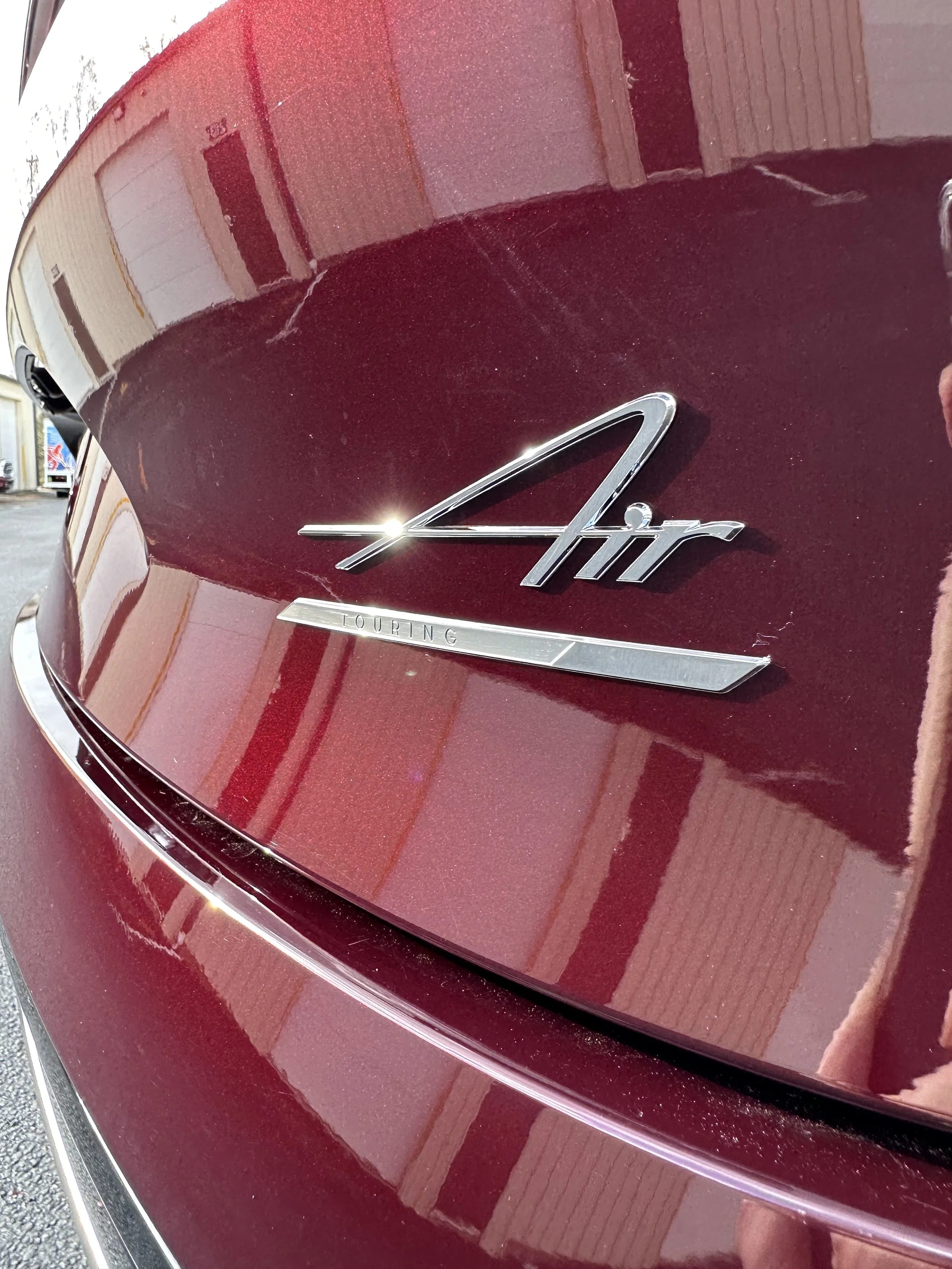 Close-up of the rear of a maroon vehicle showing an 'Air Touring' badge.