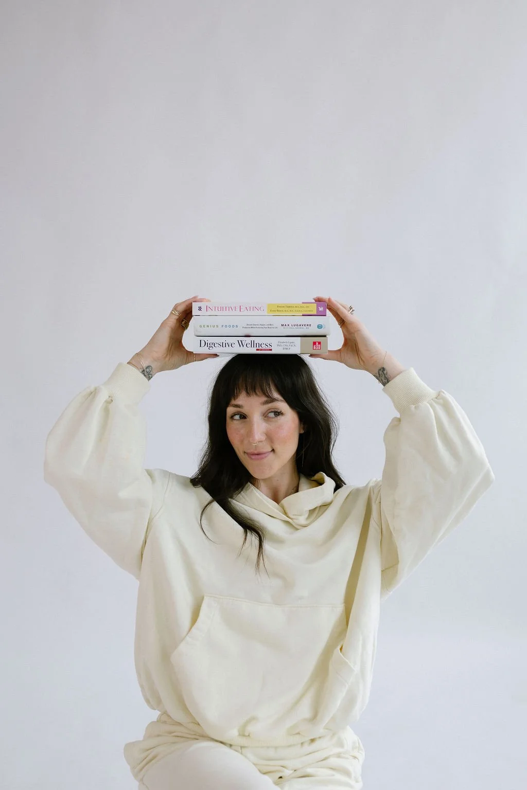 Elena Lee, Nutritional Therapy Practitioner, balances a stack of books on her head.
