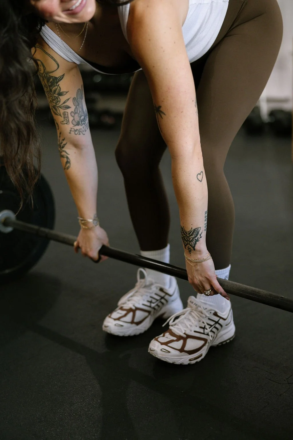 Elena Lee, women's fitness coach in Dallas, leans forward to dead lift a bar with weights.