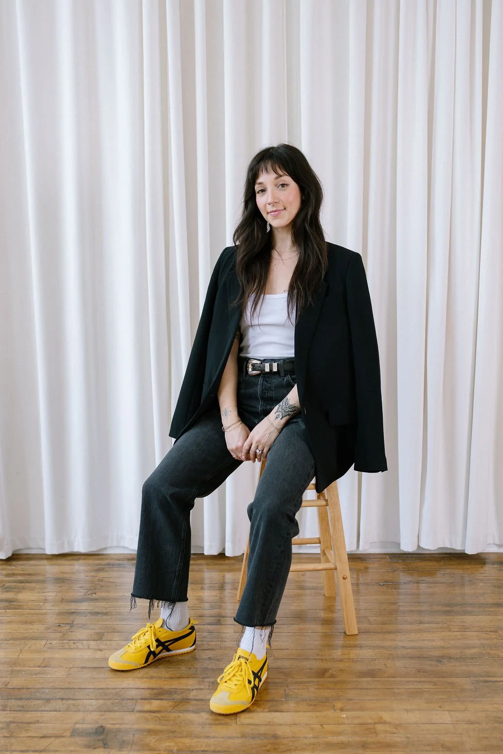 Elena Lee, personal trainer and nutrition coach for women in Dallas, sits on a stool in business casual clothing.