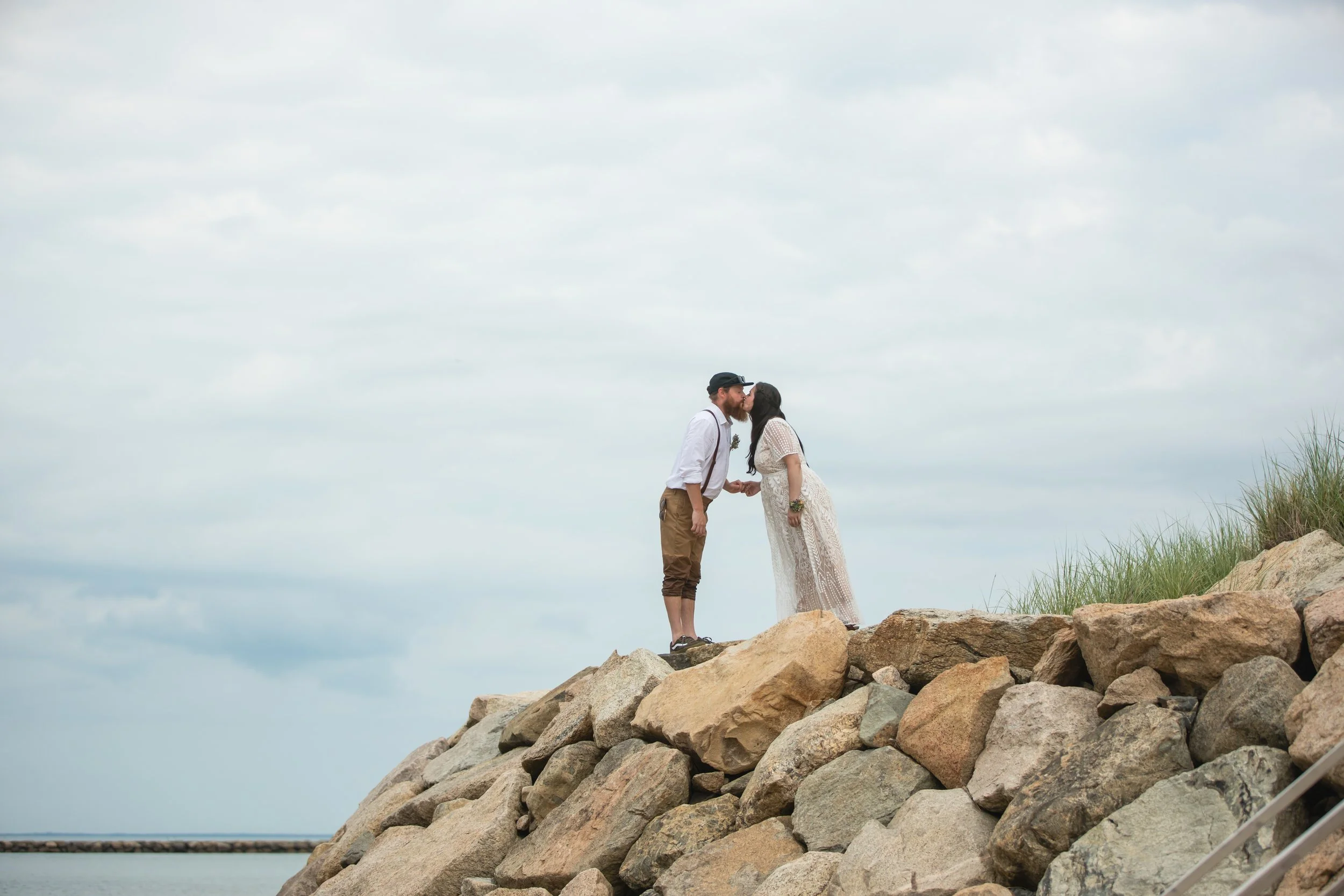 Loving moment on rocks newly married Cape Cod
