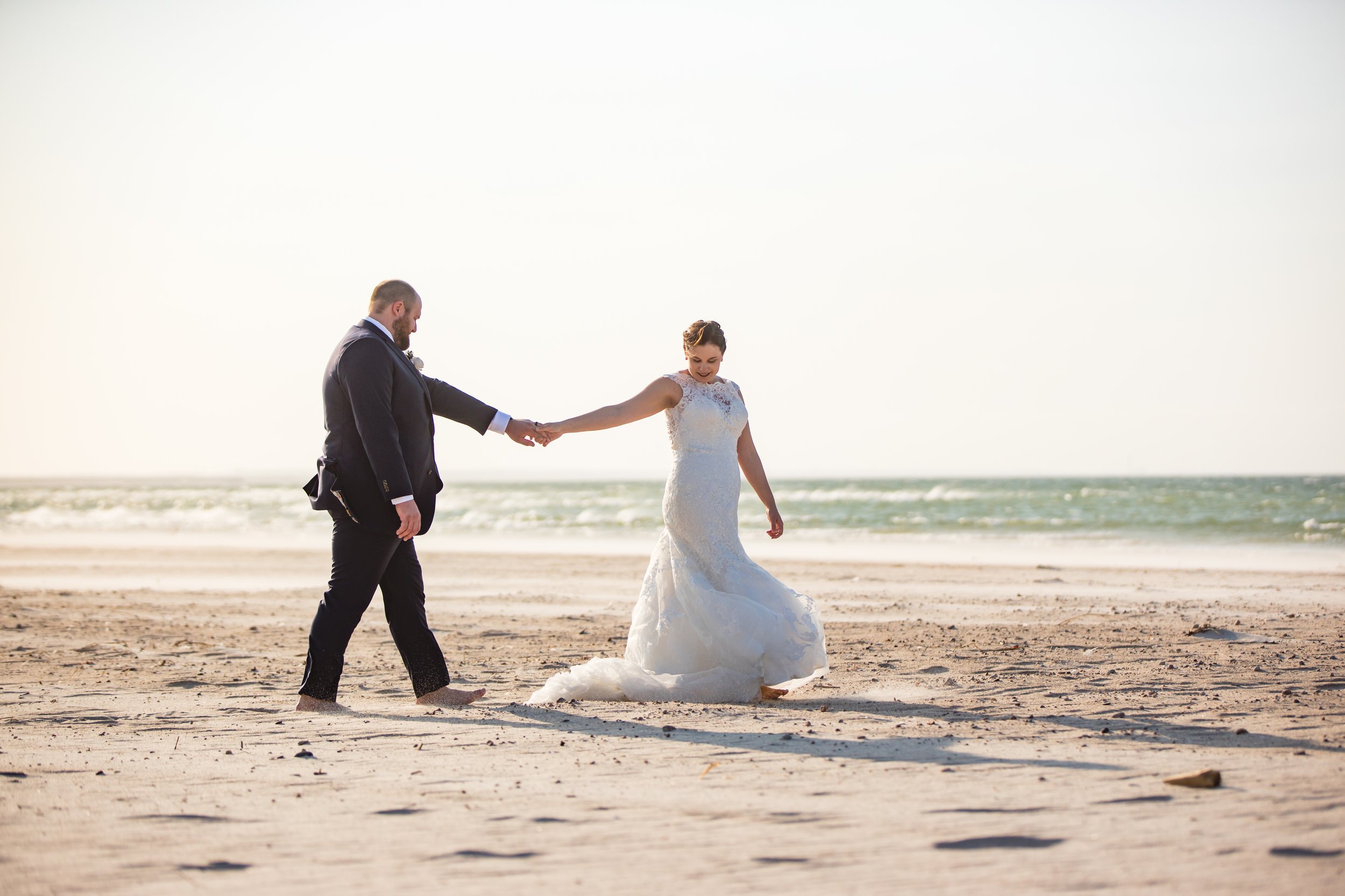 Fun beach wedding portrait couple holding hands