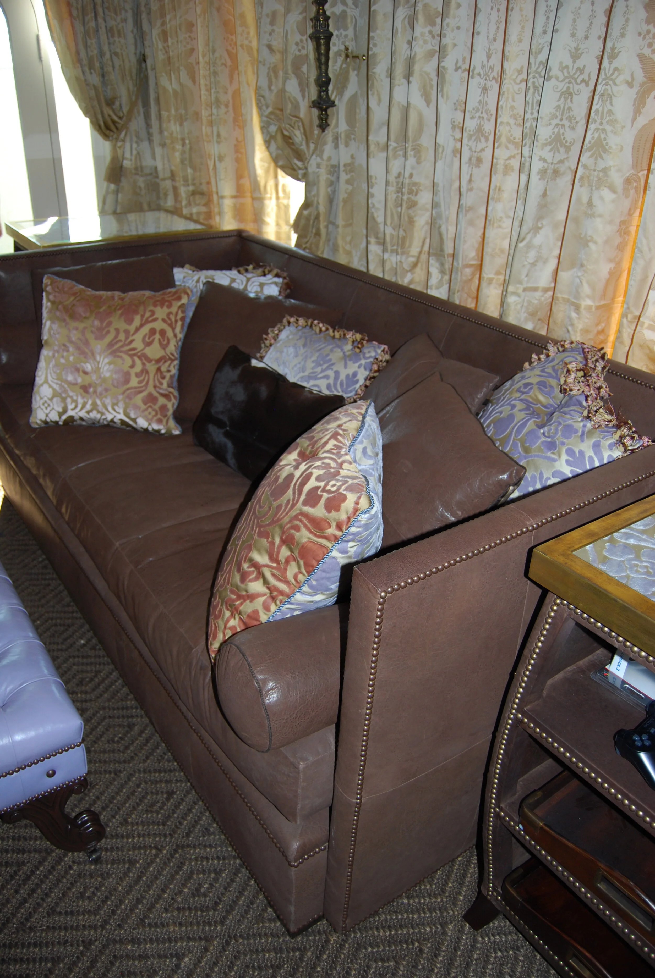  custom sofa with custom pillows and draperies  custom leather upholstered ottomans and leather side tables 