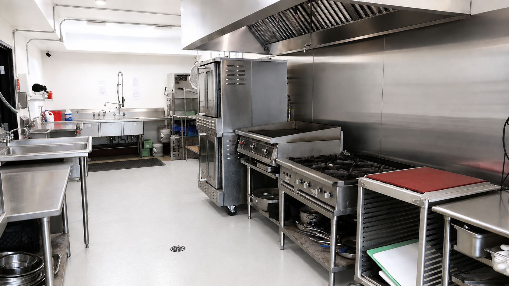 Gourmet Garage commercial commissary kitchen with ranges, ovens, ventilation hood, prep tables, and sinks