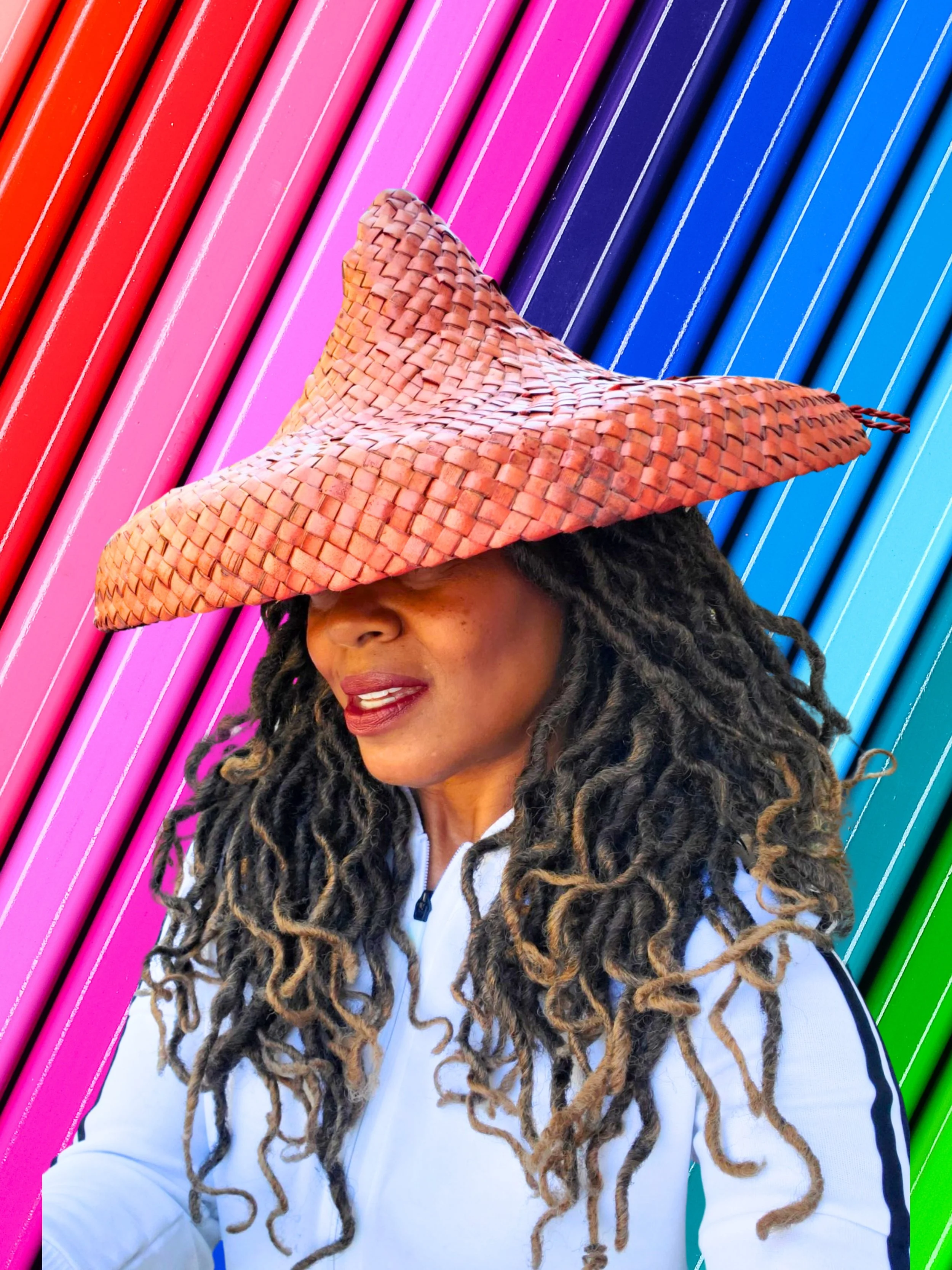Person wearing a woven straw hat with colorful striped background.