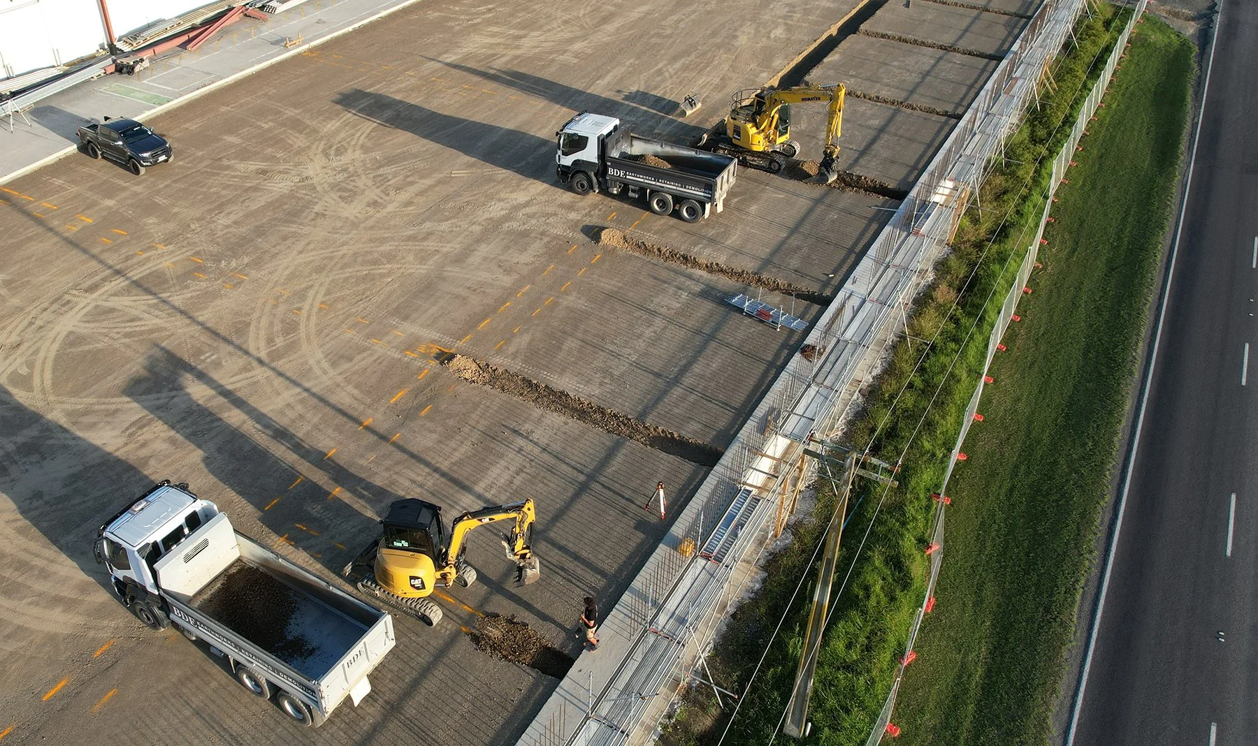 Aerial view of BDE trucks and diggers preparing a large commercial site beside a highway