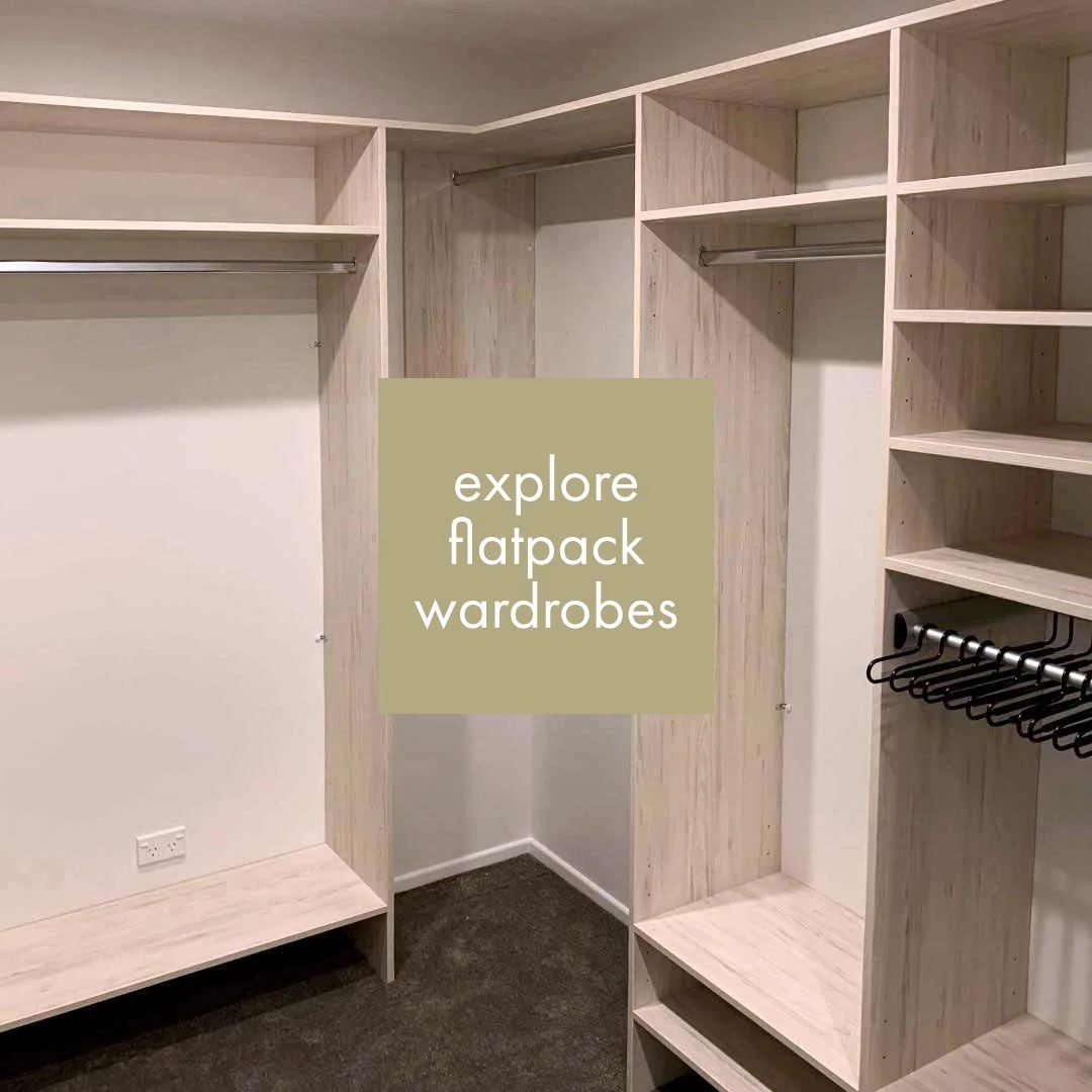 Empty walk-in closet with light wood shelving, hanging rods, and black hangers. Text overlay says explore flatpack wardrobes.