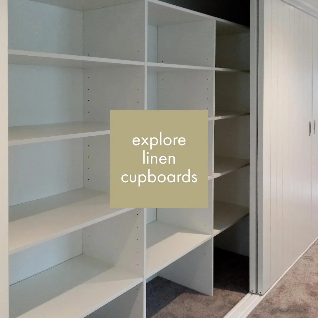 Empty white linen cupboards with open shelves and closed doors.