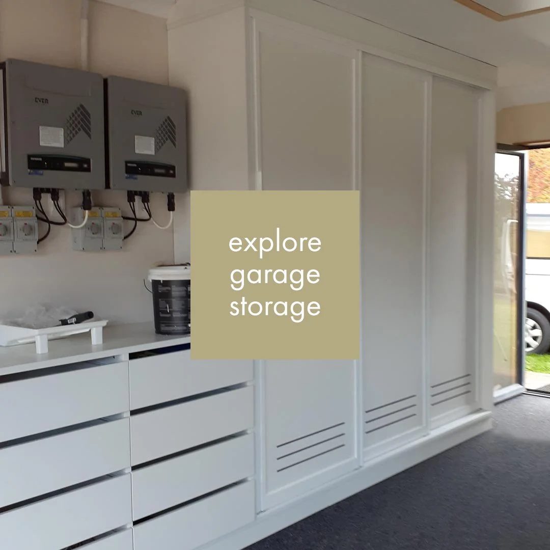 Indoor garage storage with white cabinets, electrical panels on the wall, and a sliding door to the outside.