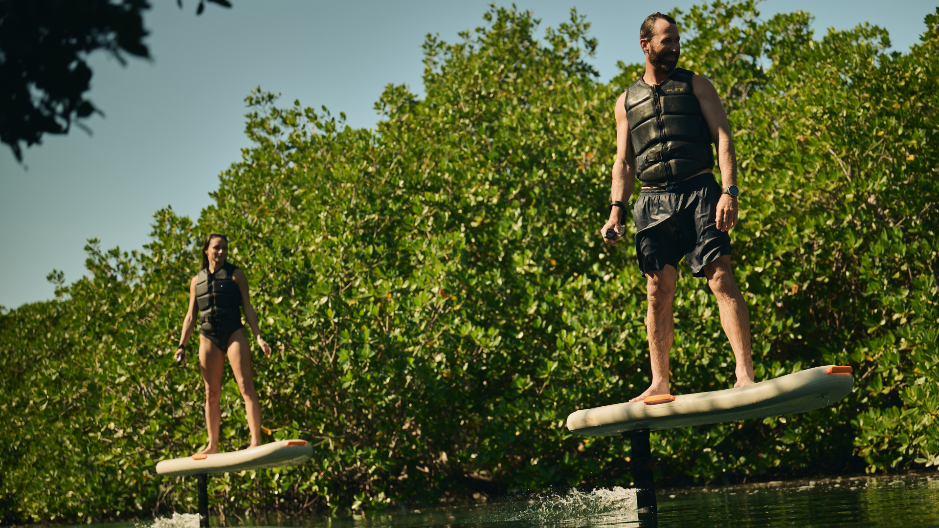 Two riders eFoiling on Fliteboard AIR inflatable boards in Sabbia color on open water
