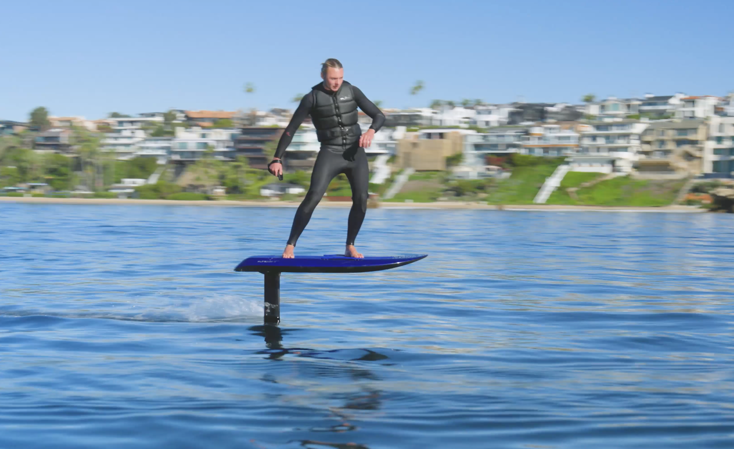 Fliteboarding in Crystal Cove, CA with one rider flying above the ocean, showcasing smooth conditions and the beauty of the Southern California coast.