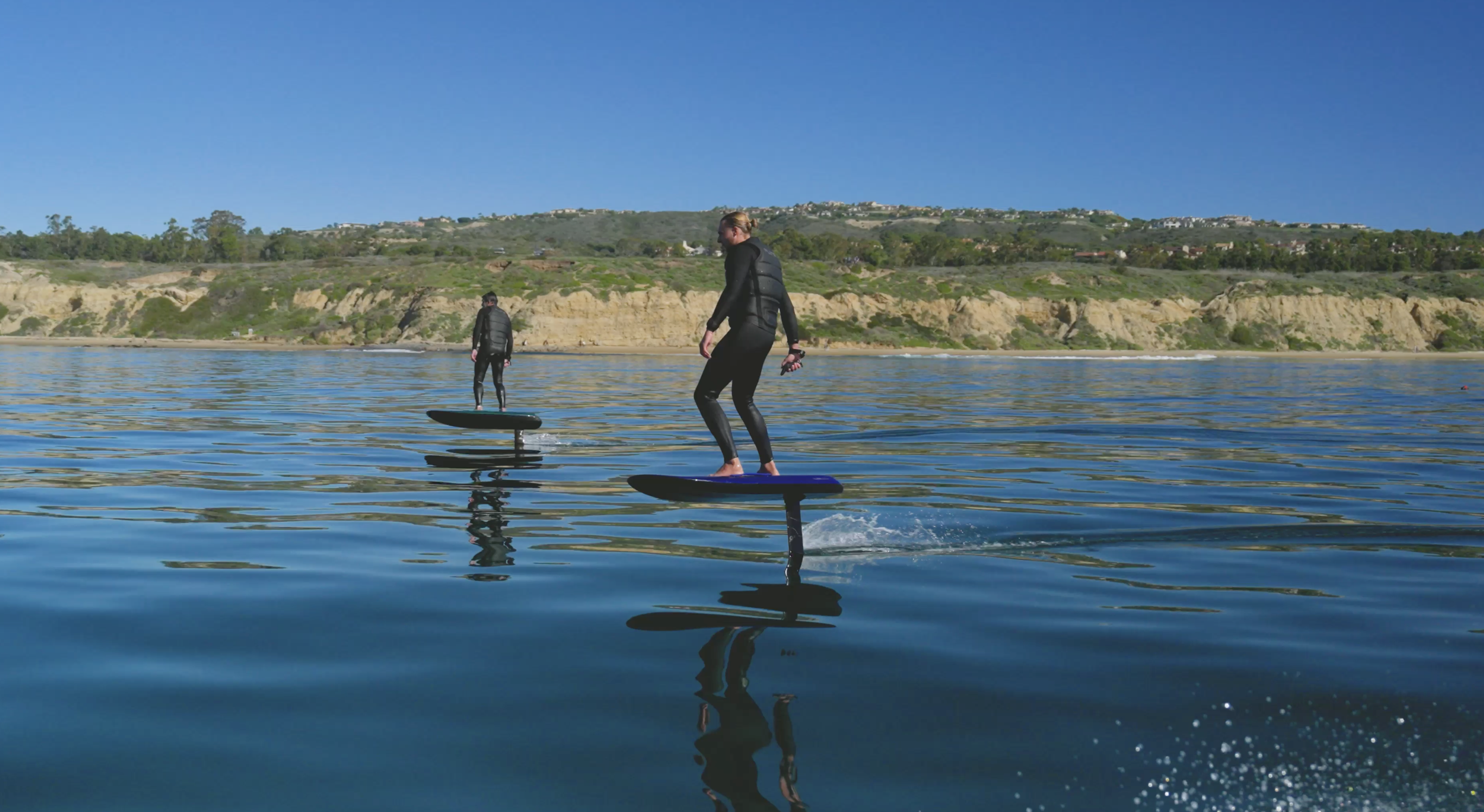 Two riders fliteboarding in Crystal Cove, Orange County, experiencing the excitement of eFoiling along the Southern California coast.