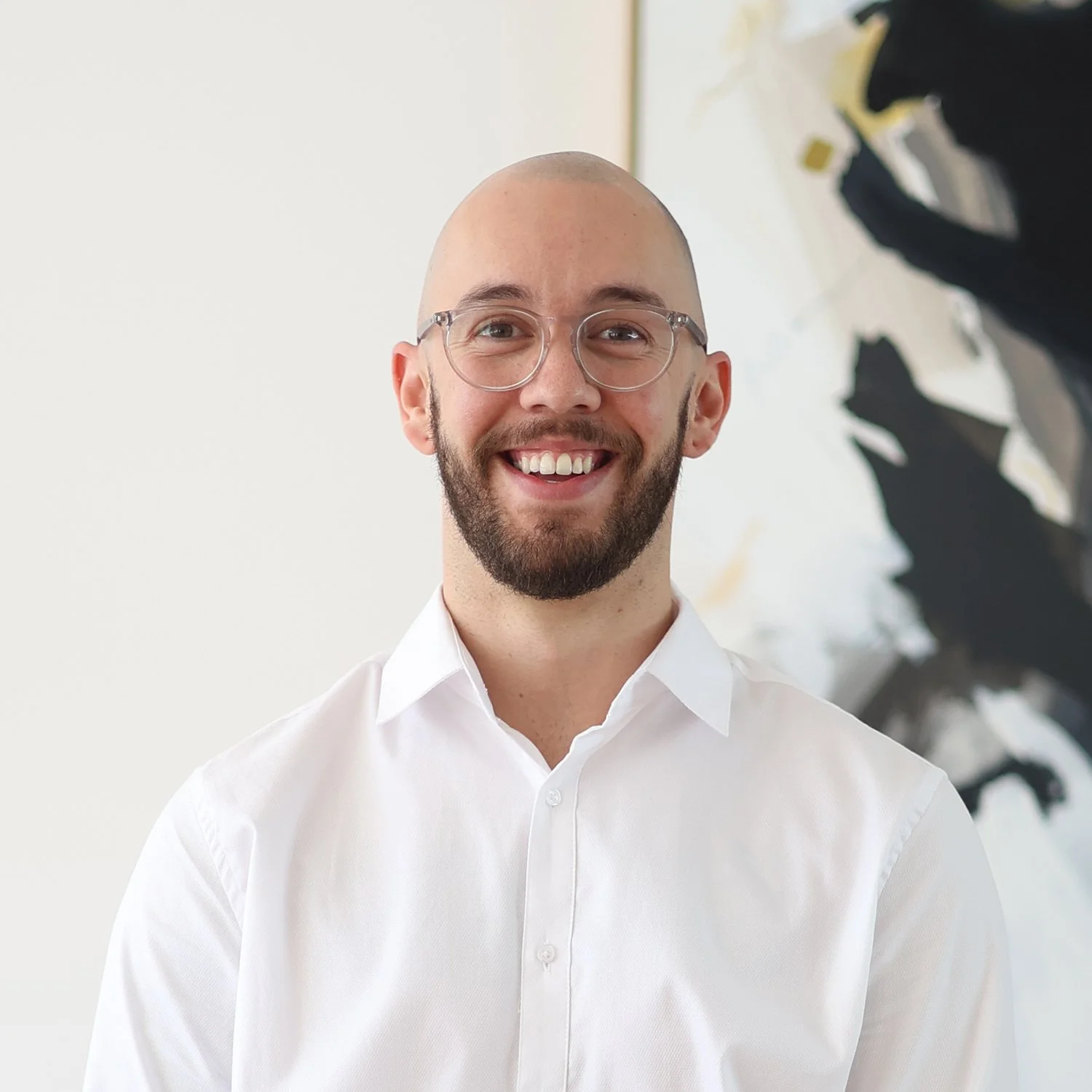 Kai Bettison, Credit Analyst at Sphere Home Loans with a beard and glasses wearing a white dress shirt.