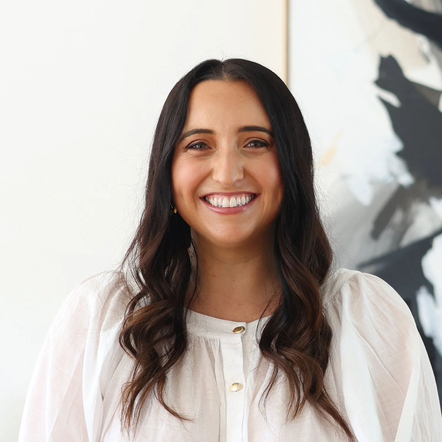 Courtney Horwood, Parabroker at Sphere Home Loans  with long, dark hair smiling, wearing a white blouse.