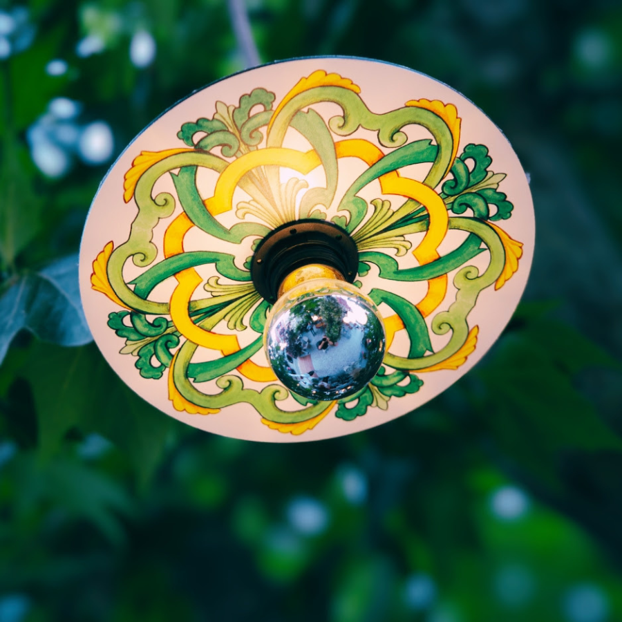A close-up photo taken outdoors of a light fixture featuring an Ellepi Maioliche shade.