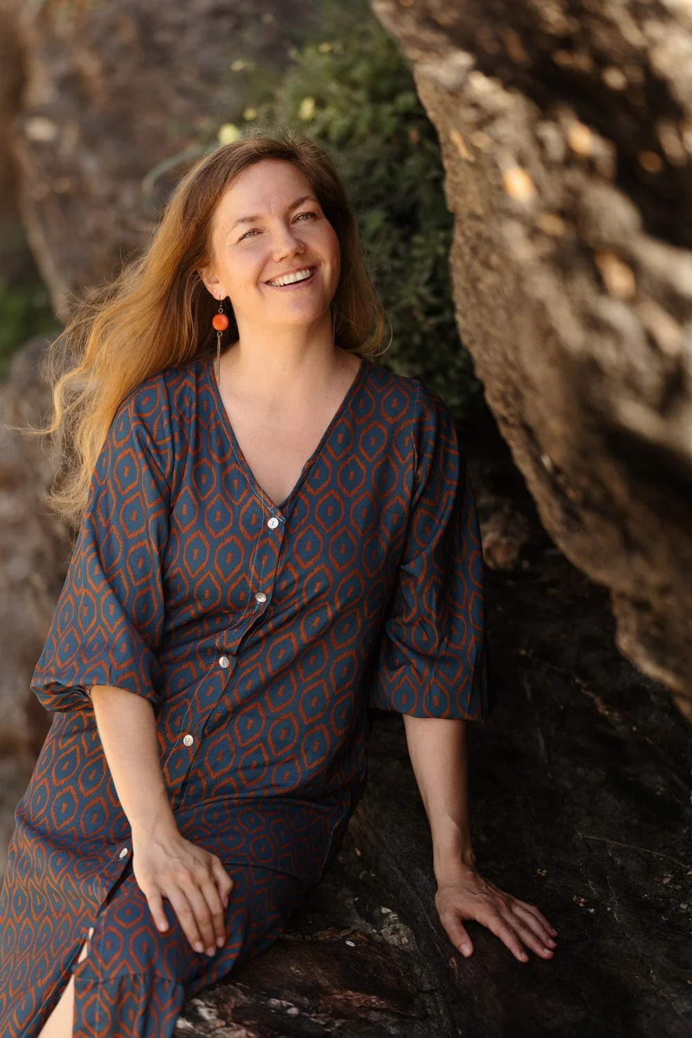 Anni Pellikka smiling at the camera by a rocky shoreline.