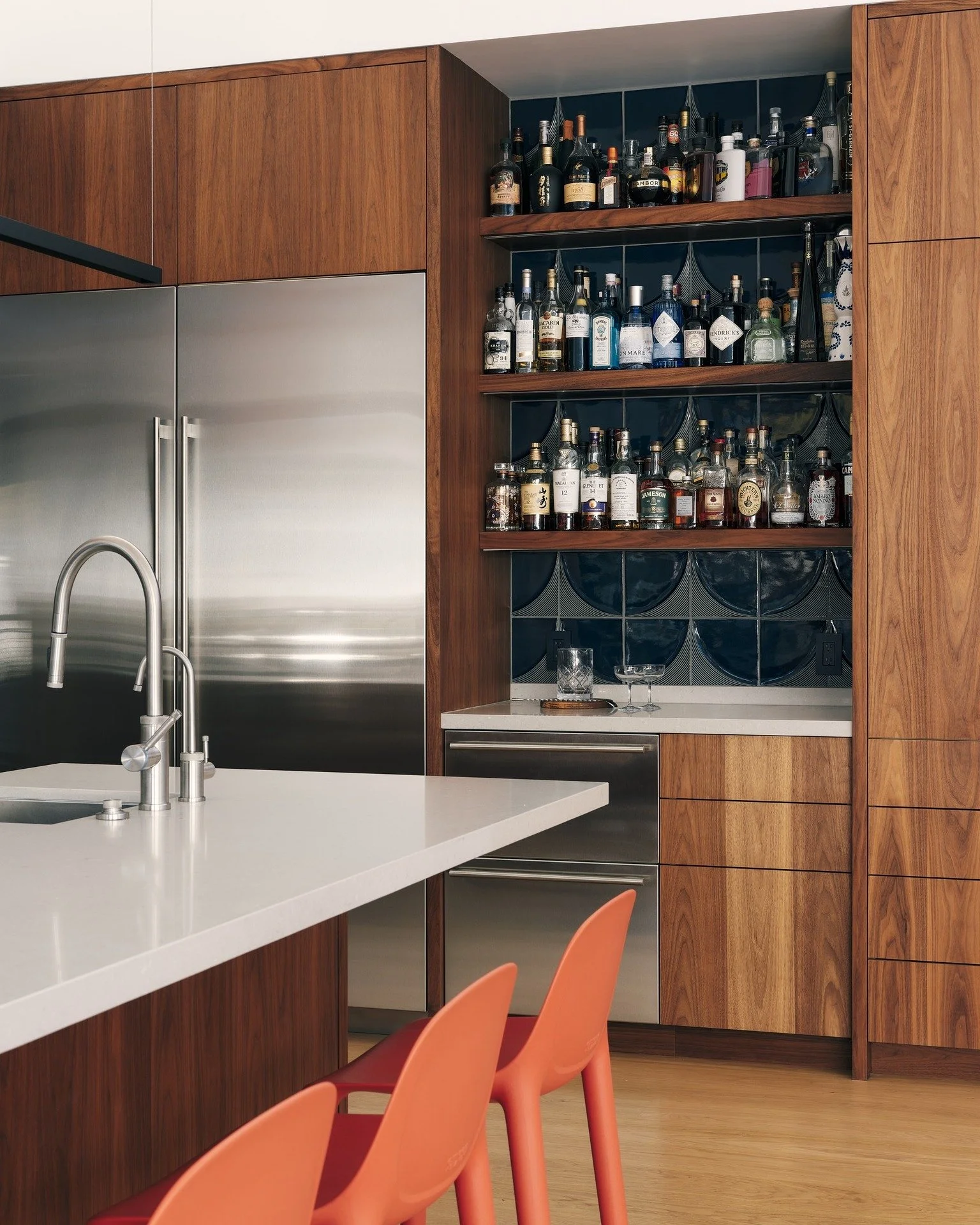 A kitchen that balances warmth, contrast, and function. 
In our #HouseOfLightAndShadow, custom richly grained walnut and white laminate cabinetry pairs with @annsacks tile, @caesarstoneus countertops, stainless steel, and bold accents to create a spa