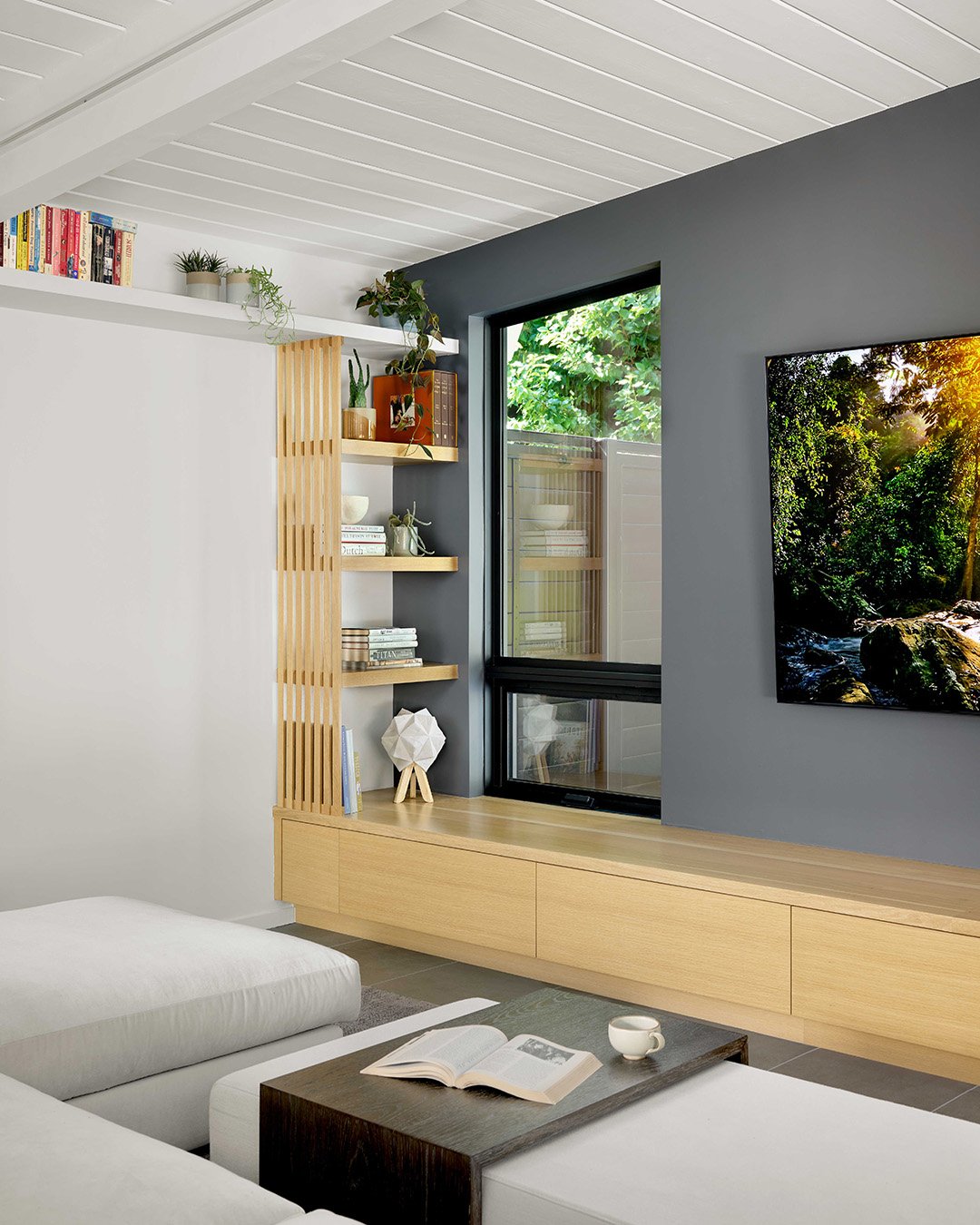 In this #Eichler remodel, we opened up the living room with a new corner window and integrated shelving above and below. This simple change brightens the space with natural light, provides display and storage, and preserves the mid-century character 