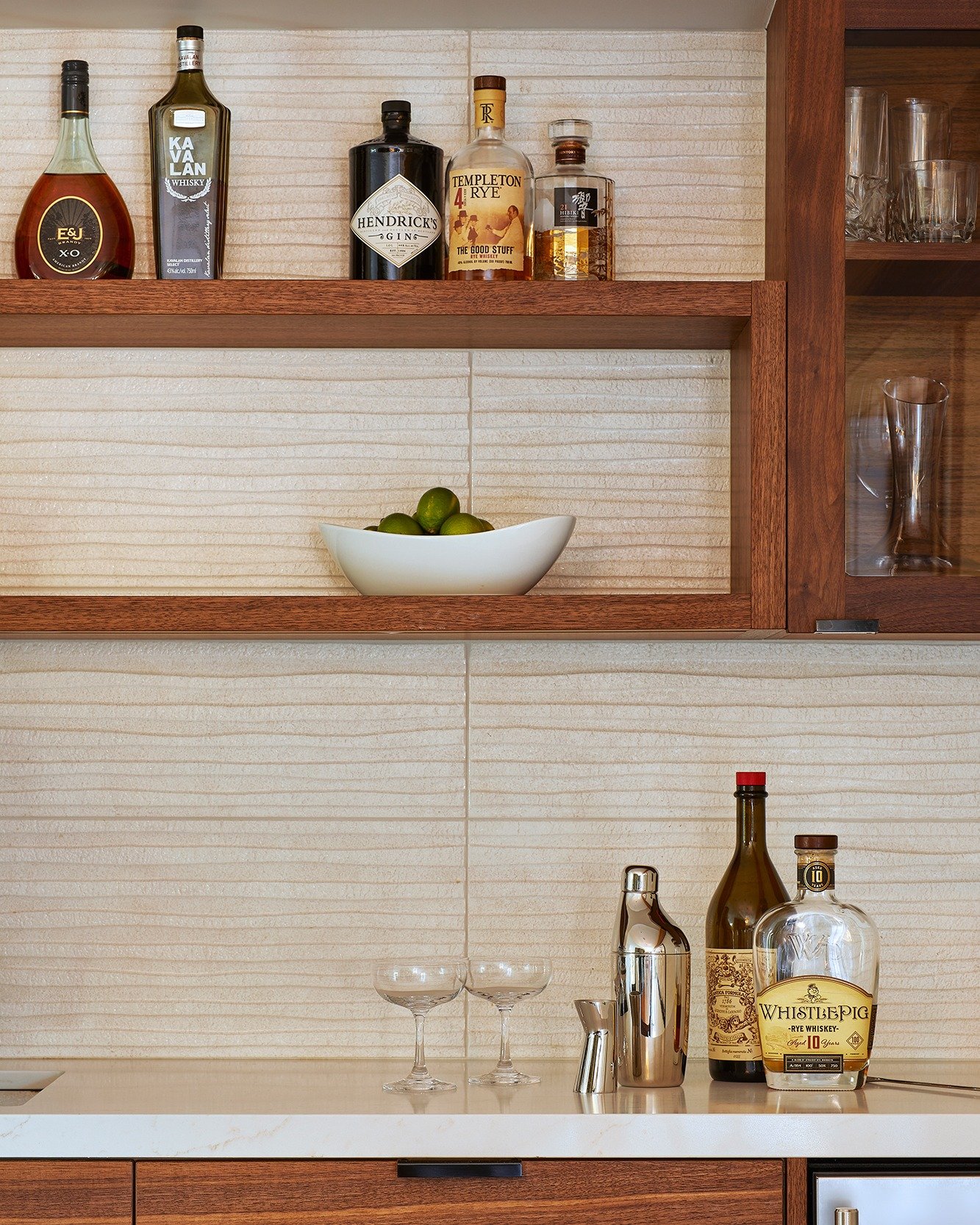 A small moment that makes the whole house feel more welcoming. At the #EngawaHouse, this built-in bar keeps everything in reach, with warm wood cabinetry, open shelving for glassware, and a quiet, textural backsplash that lets the bottles (and the li