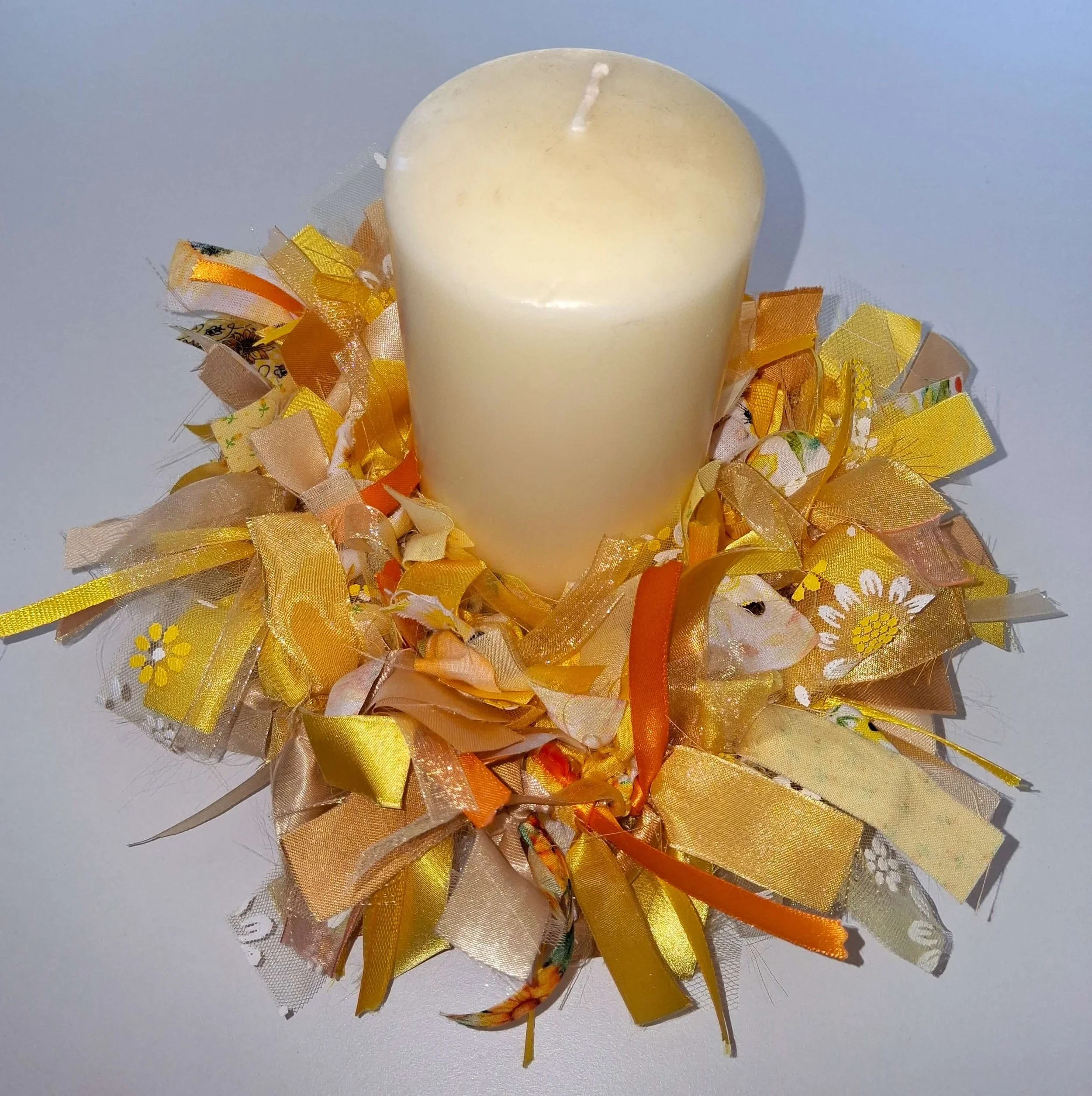 A candle decorated with yellow and orange ribbons
