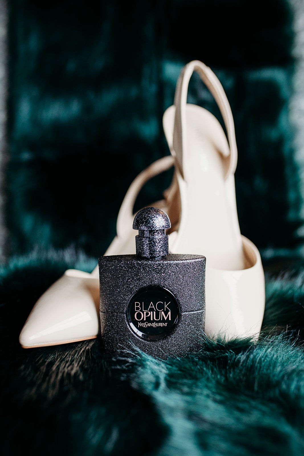 bride's shoes and perfume rest on green velvet
