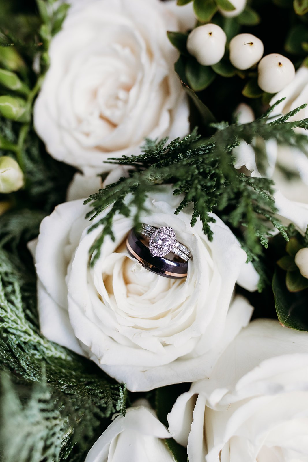 wedding bands lay on white rose in winter bouquet 