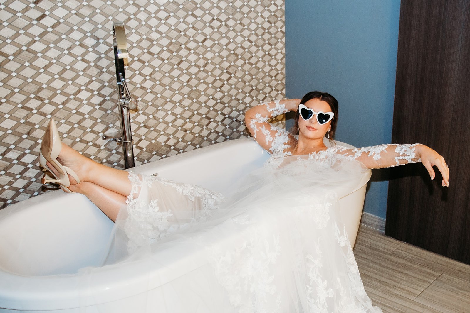 bride laughs with arm resting outside of bathtub in wedding gown