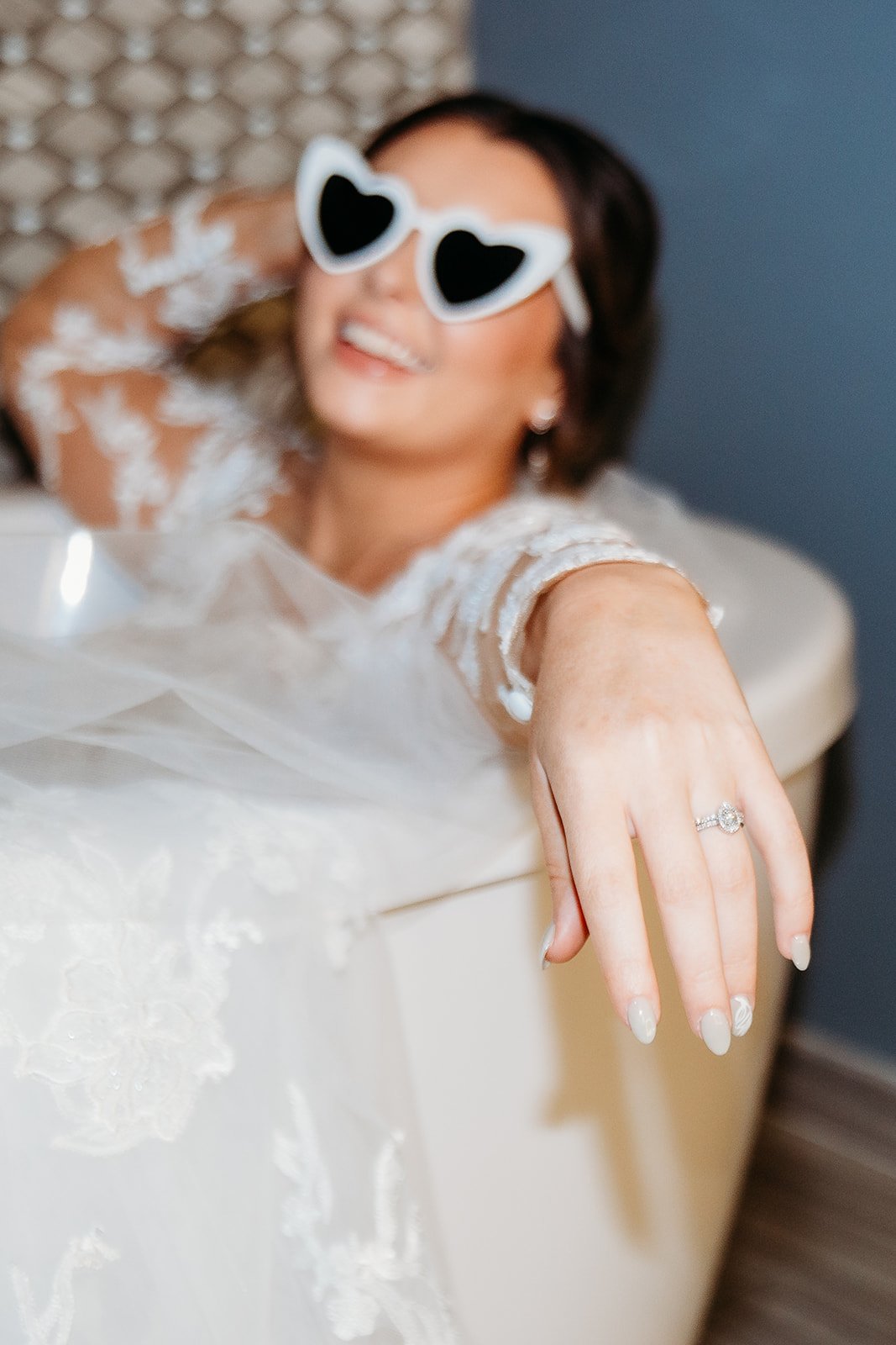 bride smiles sitting in bathtub in white heart sunglasses